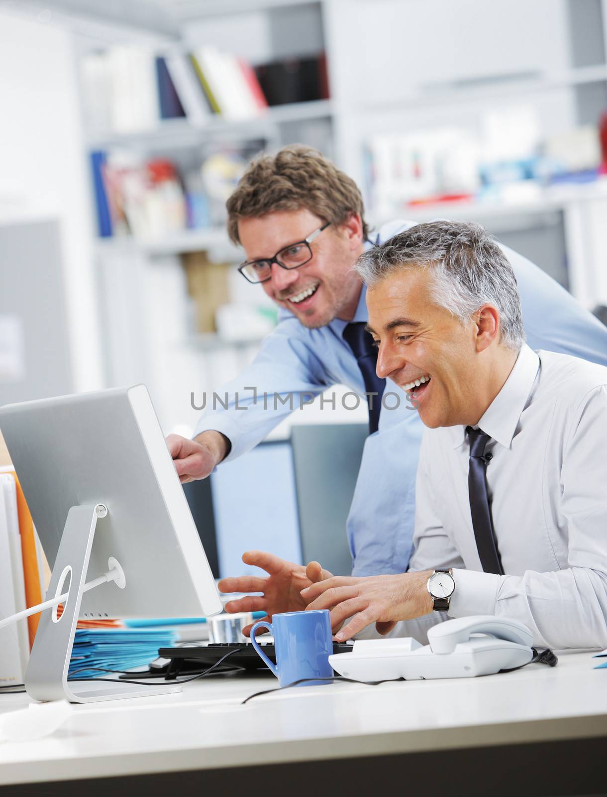 Business people laughing in front of a screen computer