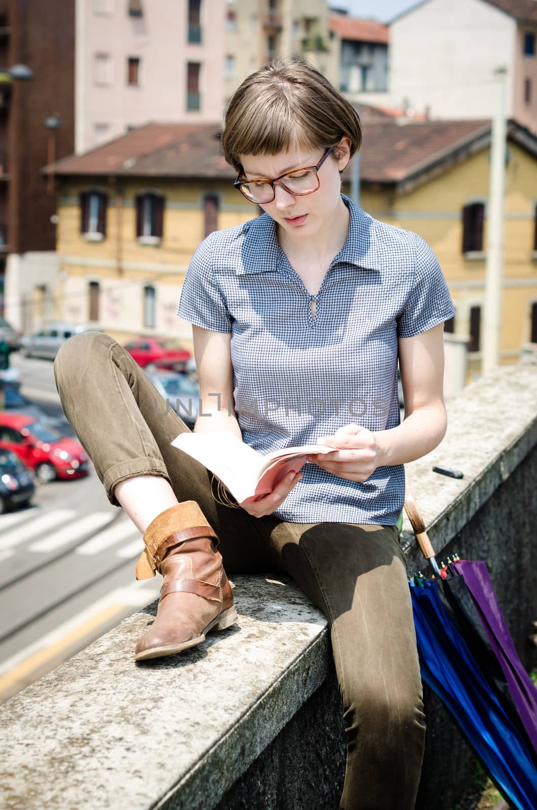 young beautiful hipster woman reading book in the city