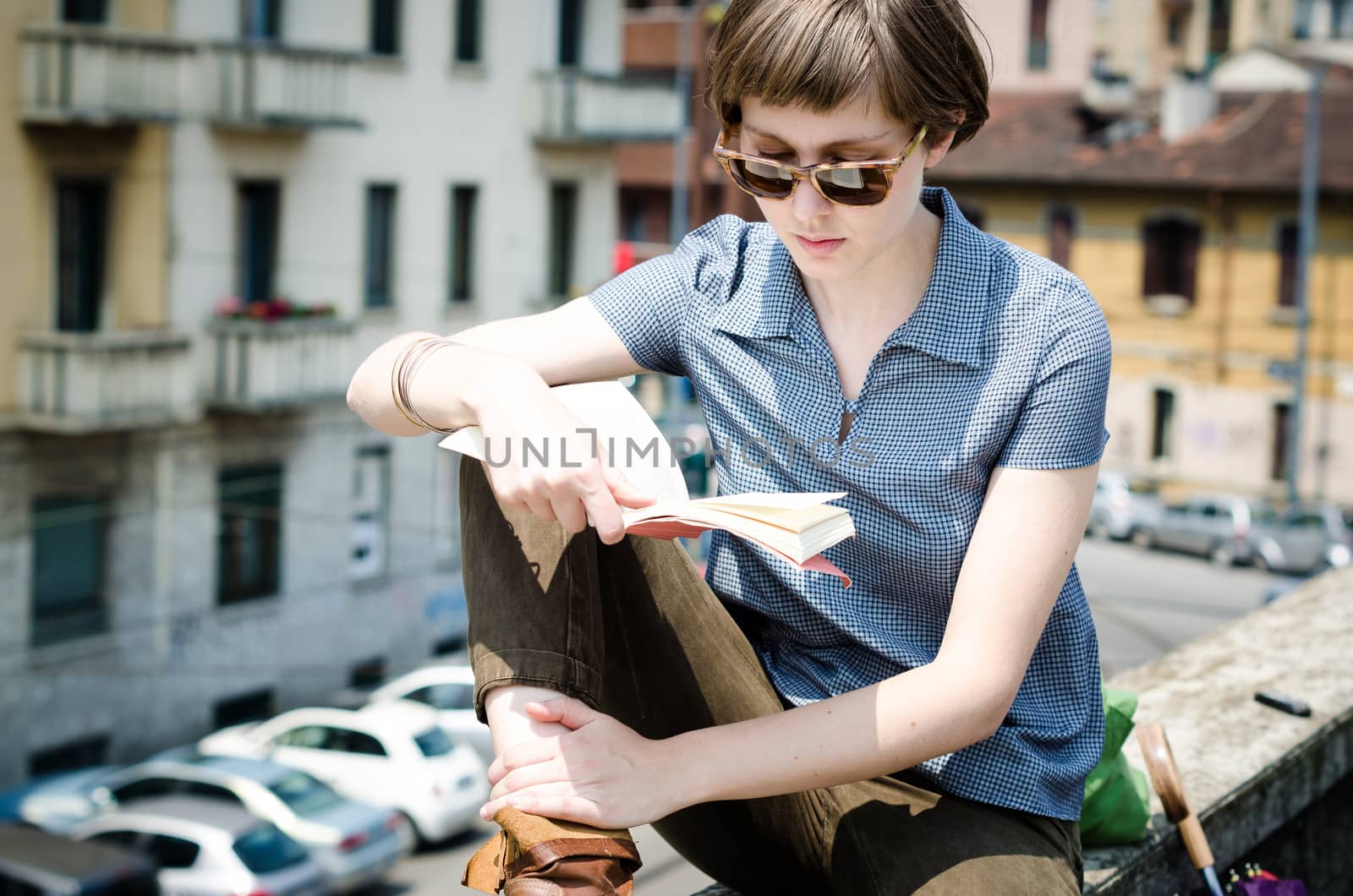 young beautiful hipster woman reading book in the city