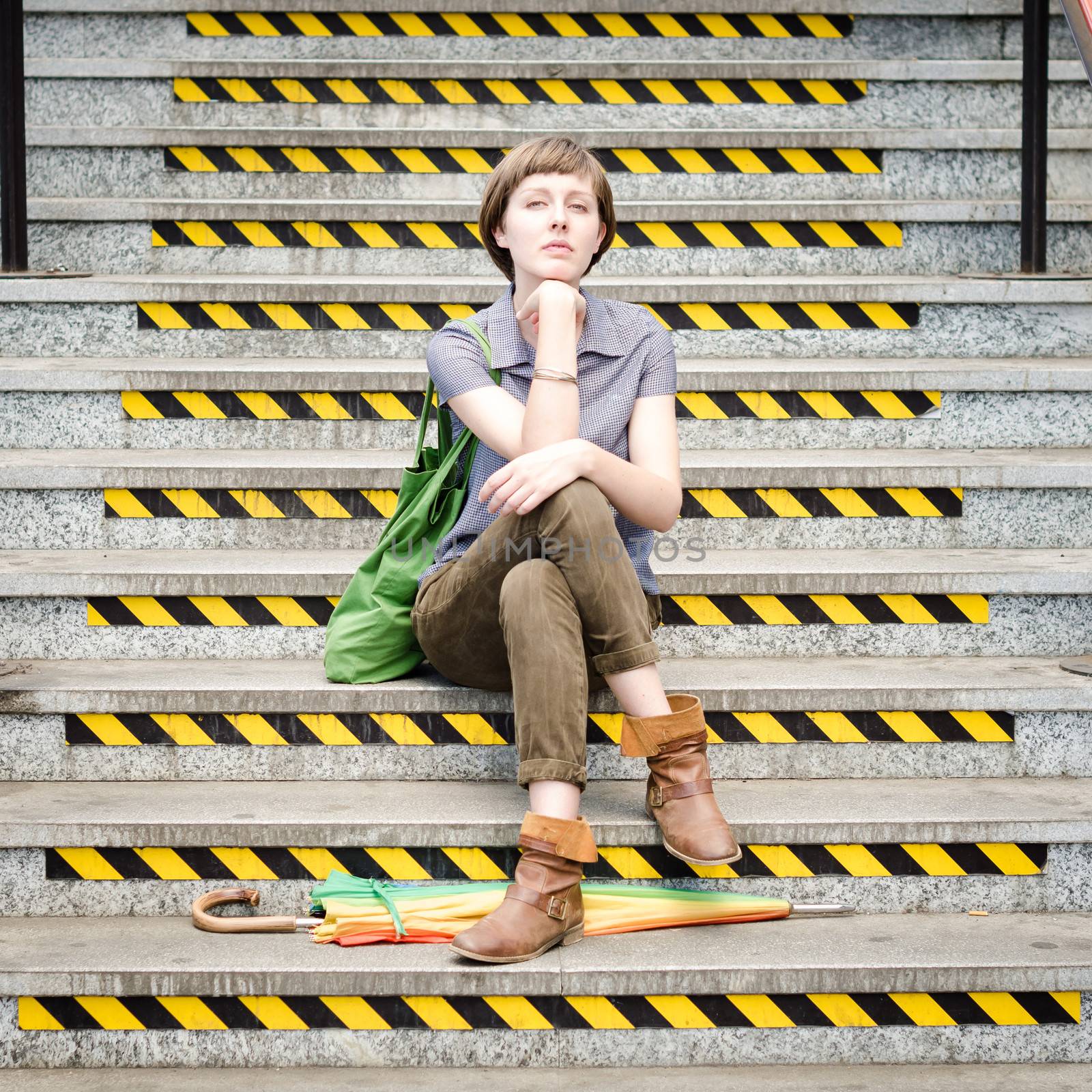 young beautiful hipster woman sitting on the stairs in the city