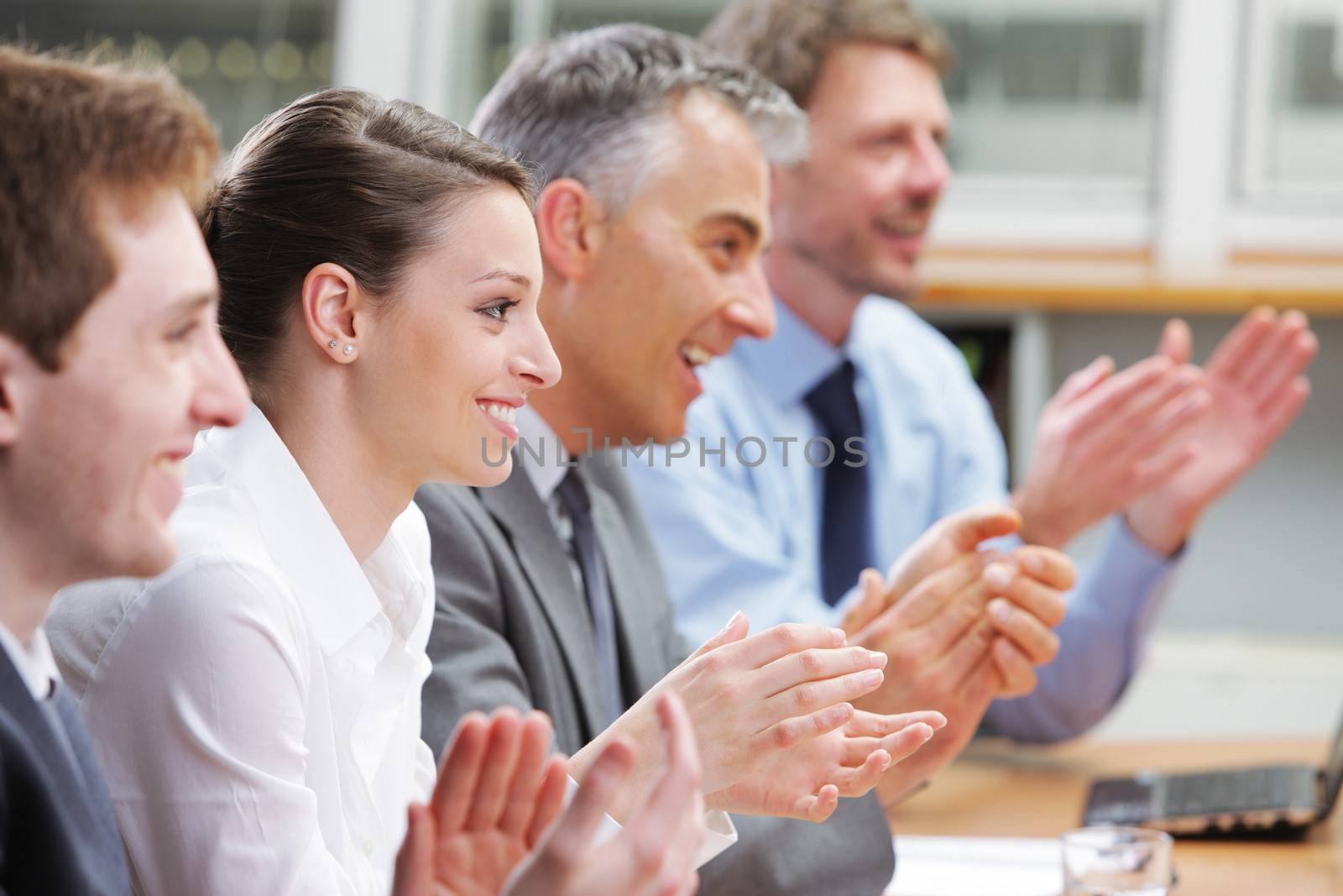 Group of cheerful businesspeople sitting in a row on a presentation and clapping