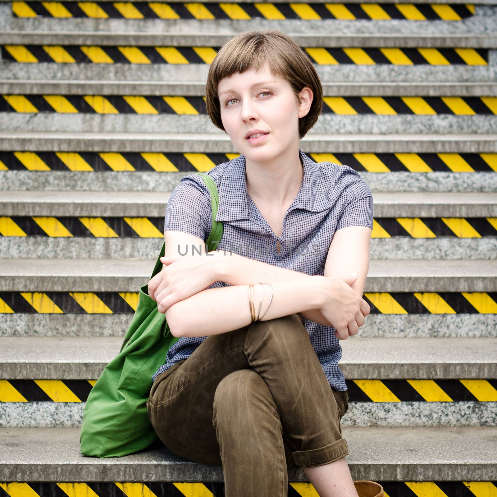 young beautiful hipster woman sitting on the stairs by peus