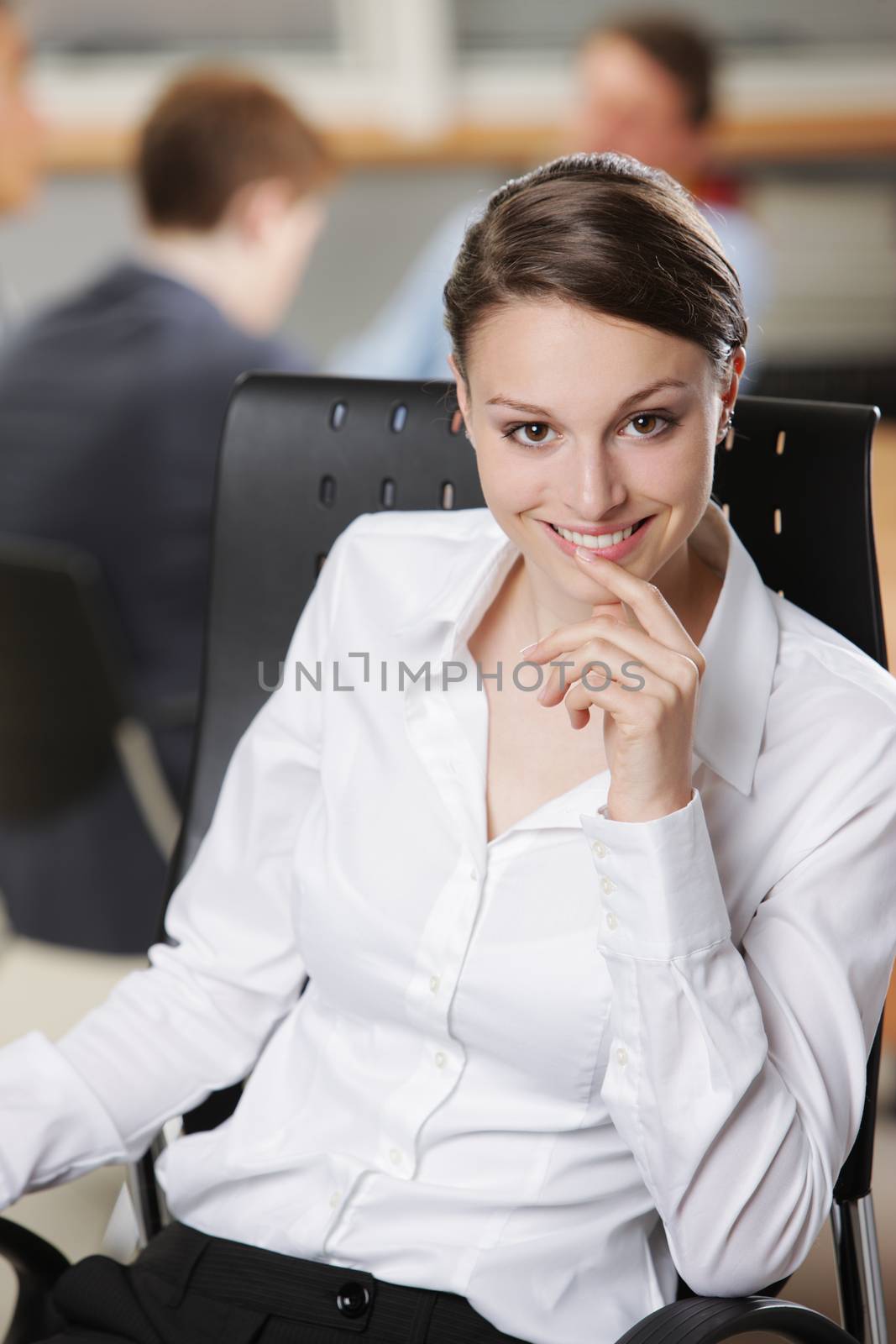 Beautiful young businesswoman with colleagues in the background