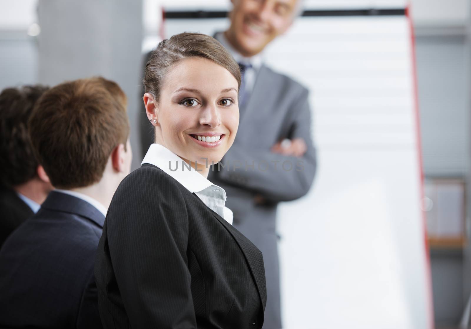 Smiling woman sitting at a business meeting with colleagues by stokkete