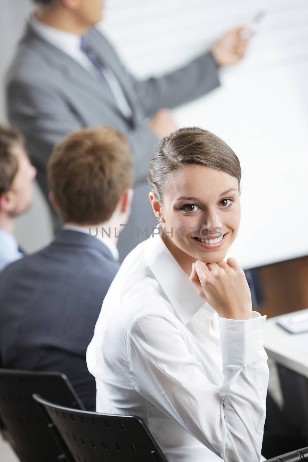 Portrait of a pretty young businesswoman smiling in a meeting with her colleagues in background