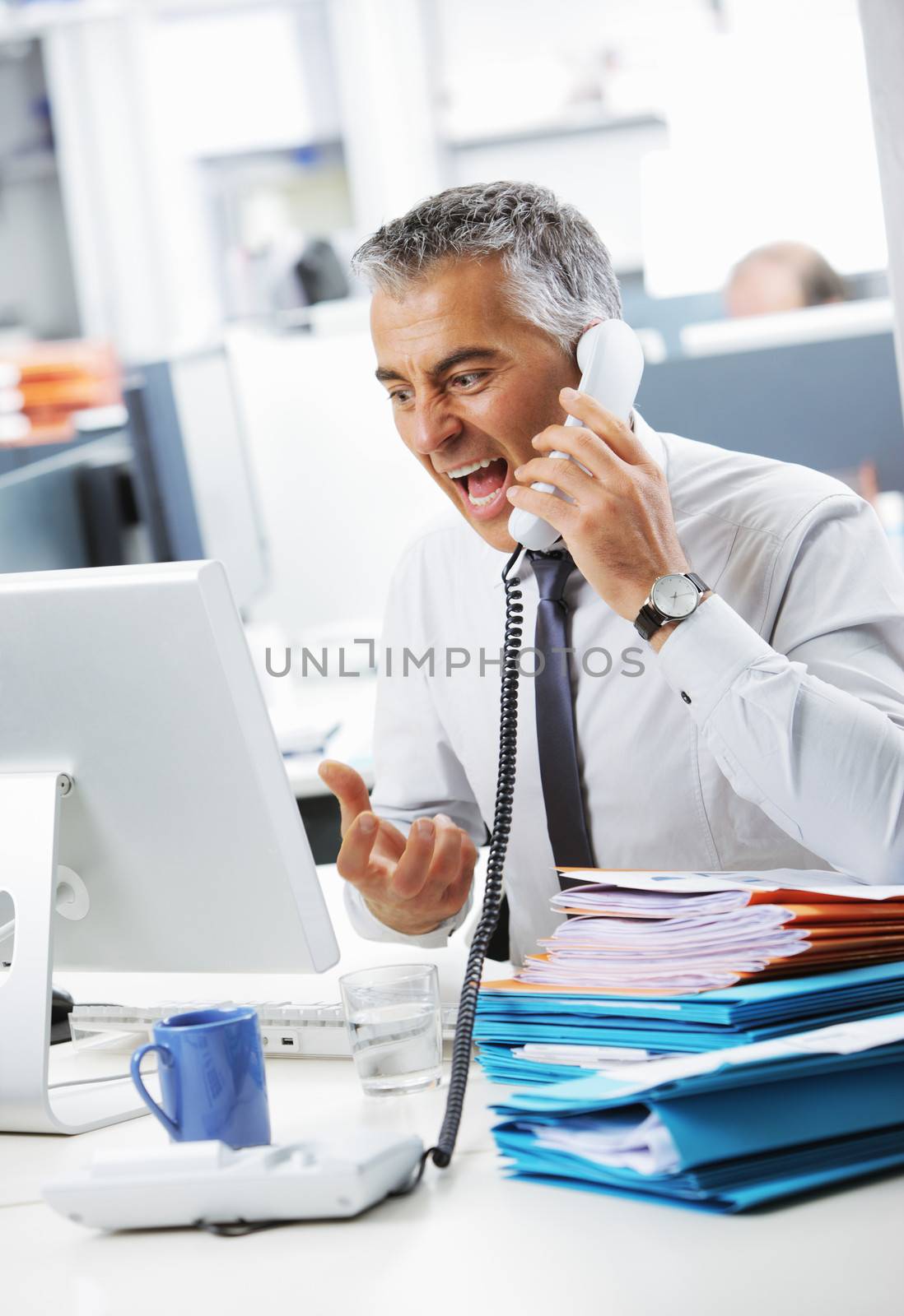Stressed business man shouting at phone in office
