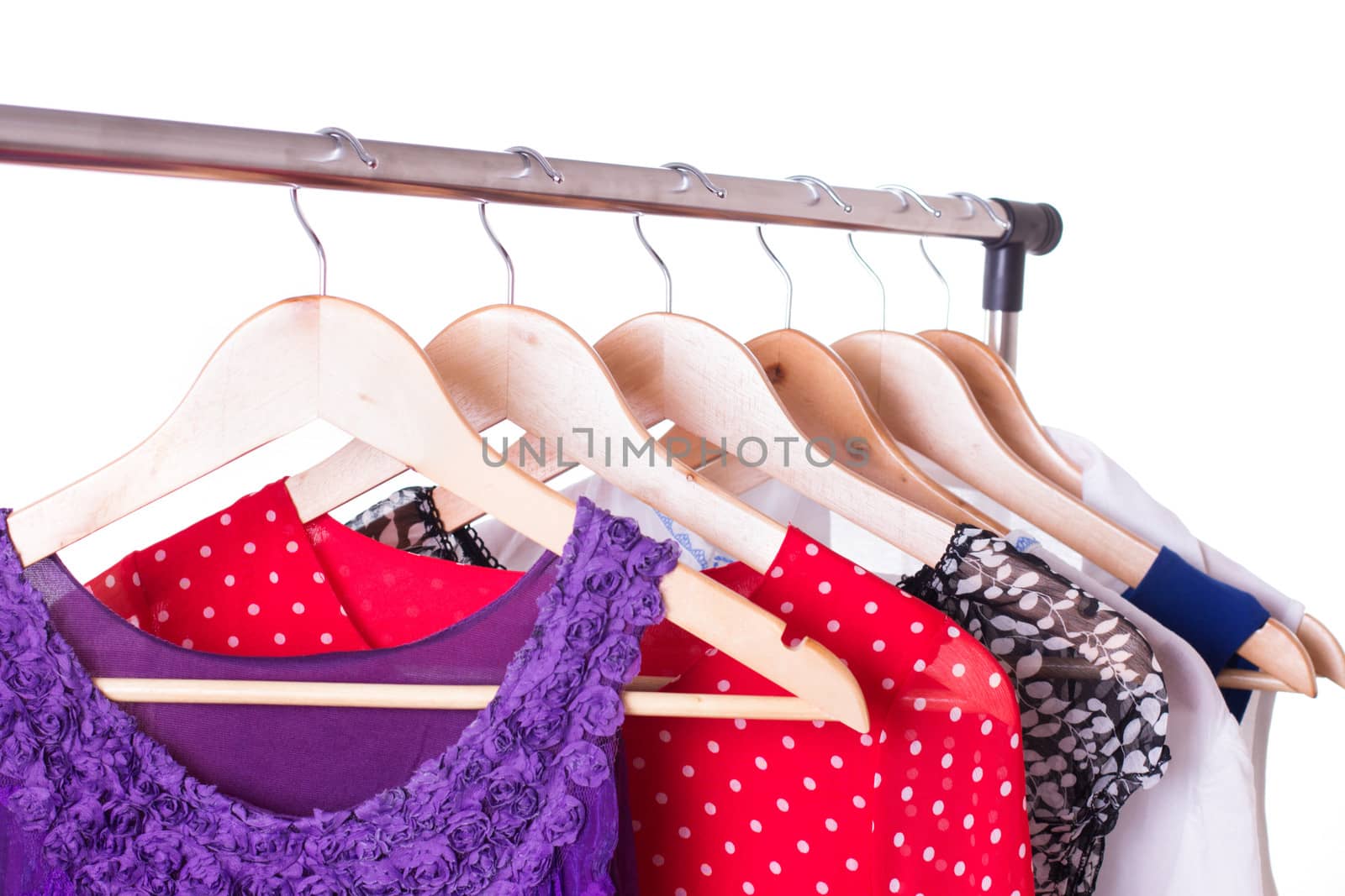 Dresses of different colors on wooden hangers over white