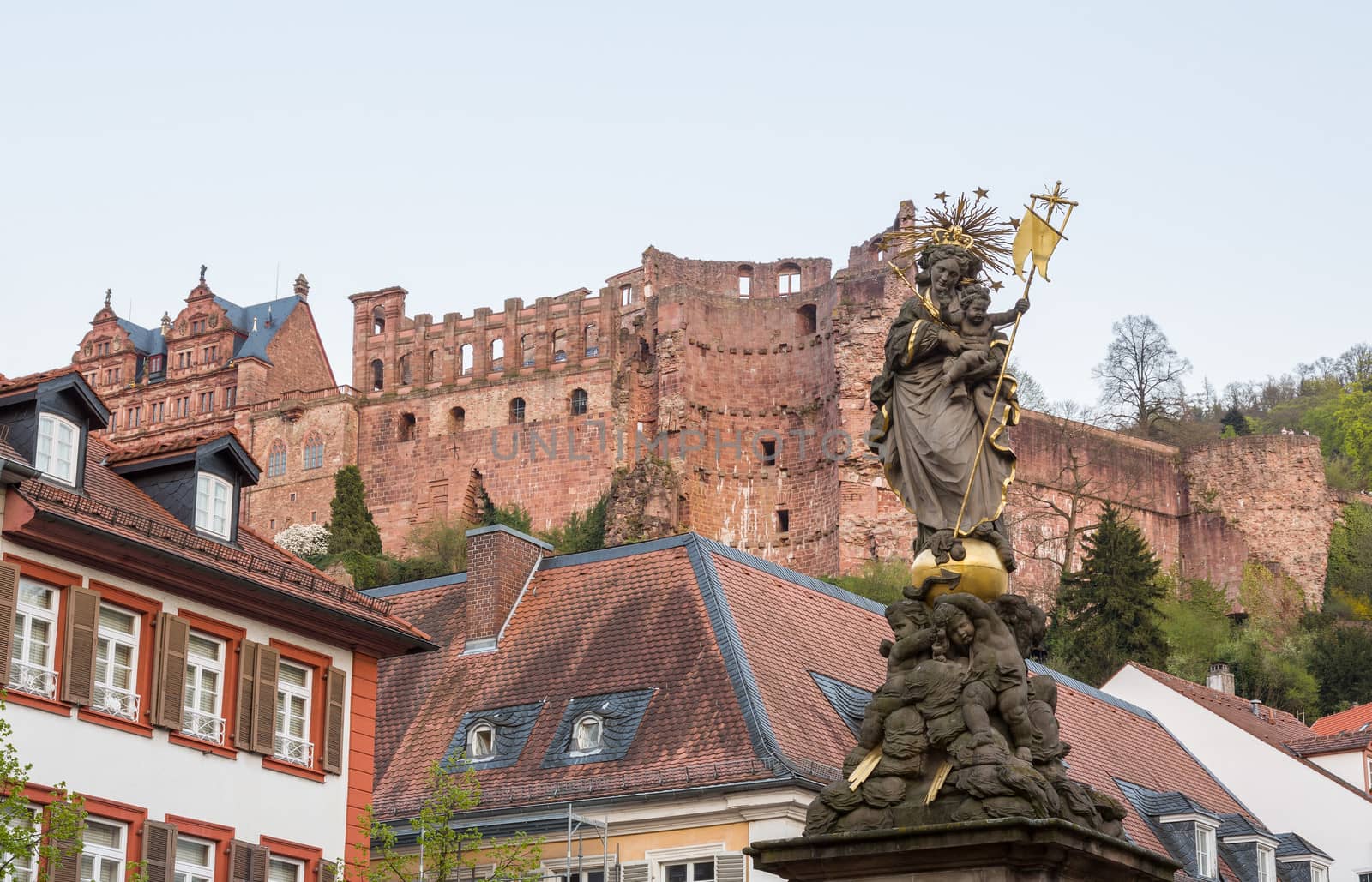 Statue of Madonna Mary and Jesus in town square of old town city of Heidelberg Germany with castle walls background