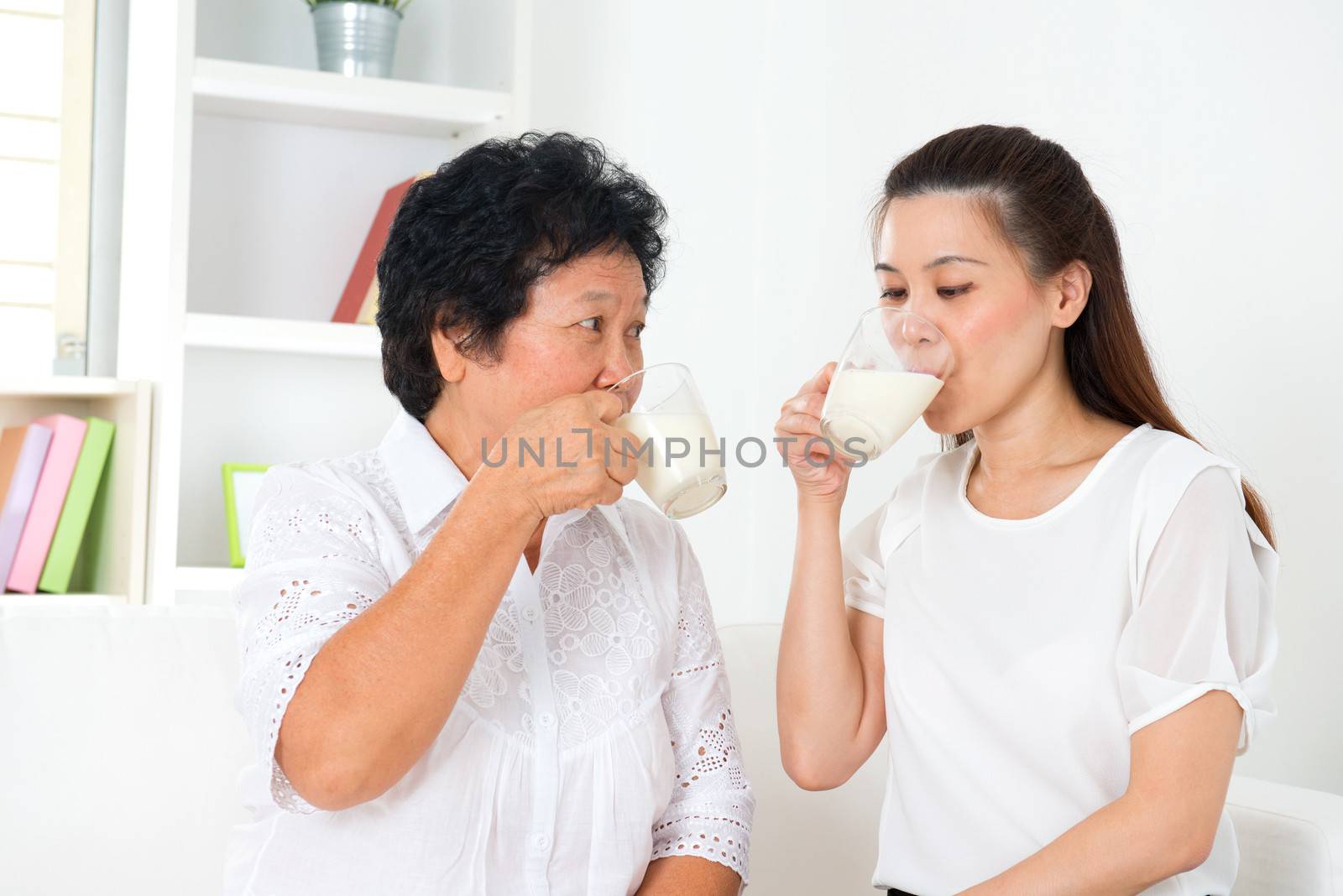 Drinking milk. Happy Asian family drinking milk at home. Beautiful senior mother and adult daughter, healthcare concept.