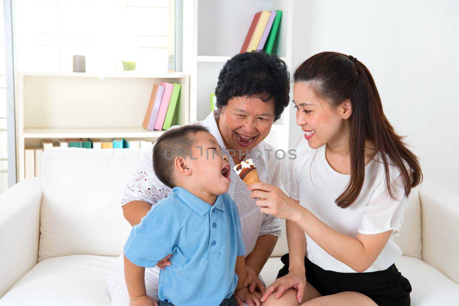 Eating ice cream. Happy Asian family at home, grandparent, parent and grandchild sharing an ice cream. Home indoor with decoration.
