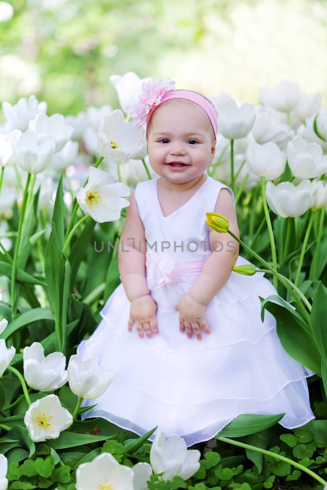 little girl in an elegant dress to stand near blossoming tulips