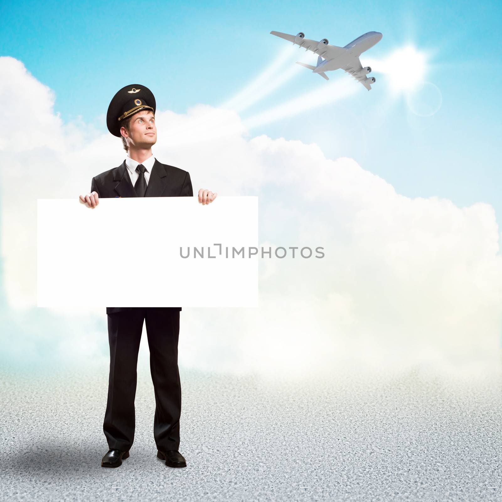 pilot in the form of holding an empty billboard on the background of sky and flying plane, place for text