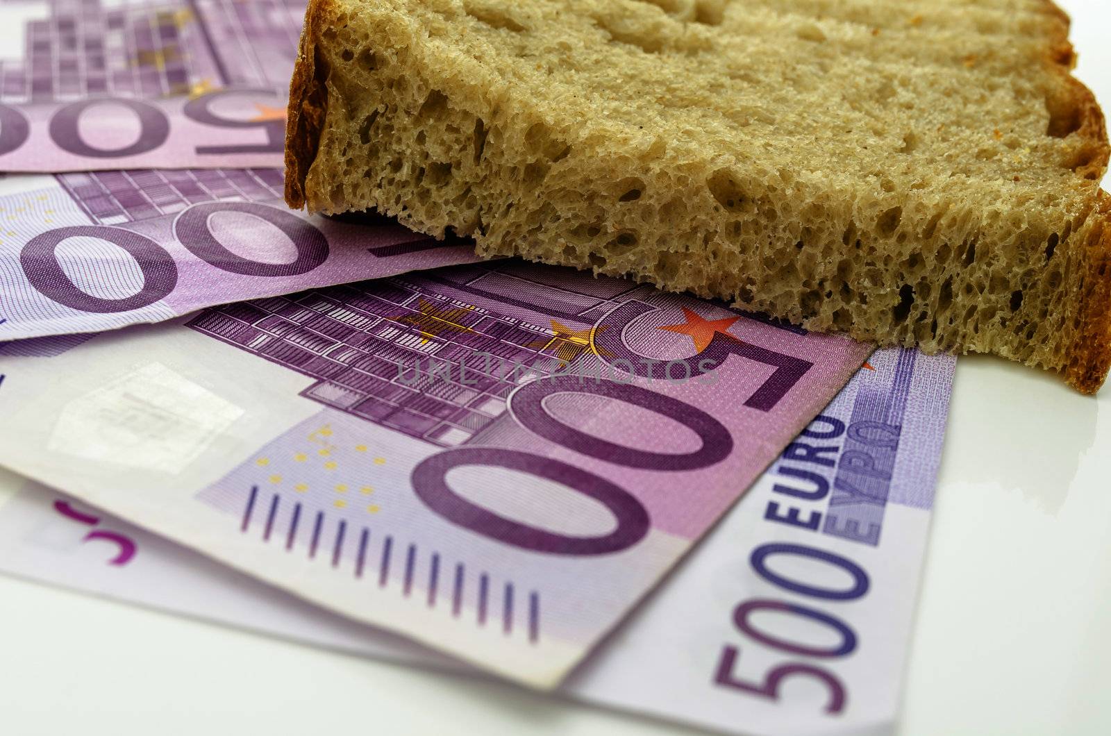 Slice of bread on Euro banknotes. Concept of big expenses food represents.