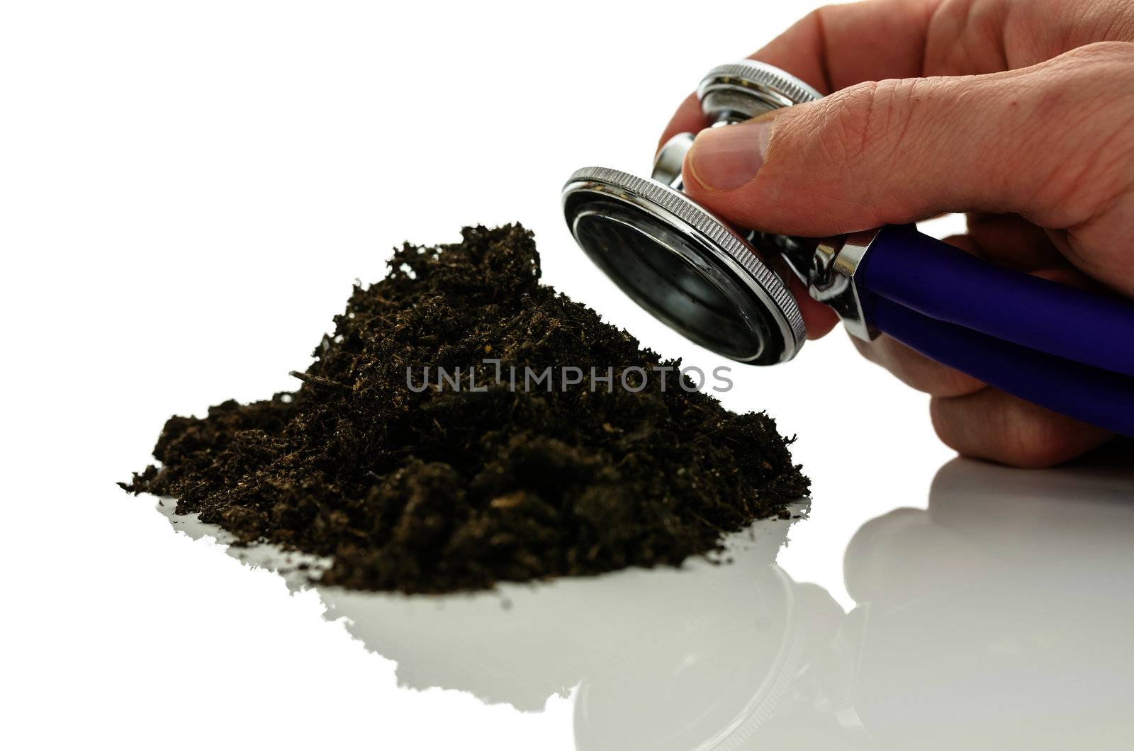 Male hand holding stethoscope over pile of soil. Concept of environmental problems chemical fertilization and pesticide cause.