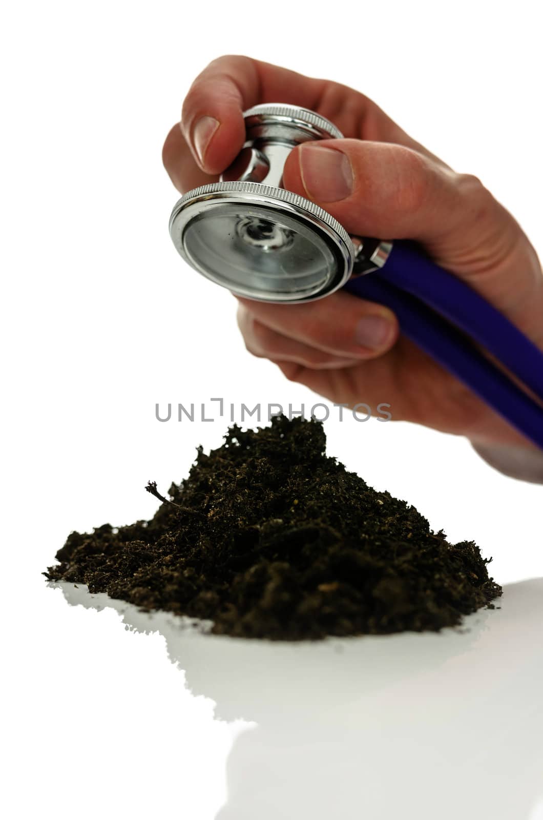 Male hand holding stethoscope over pile of soil. Concept of pollution and chemical poisoning of the earth.