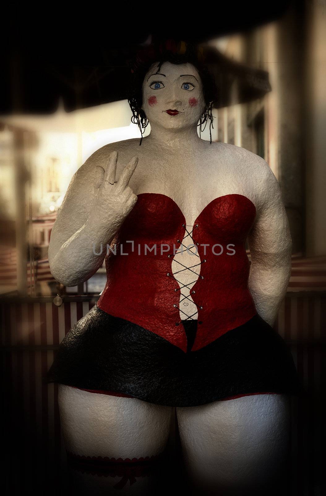 Antique well-nourished sexy female doll outside Portuguese restaurant.