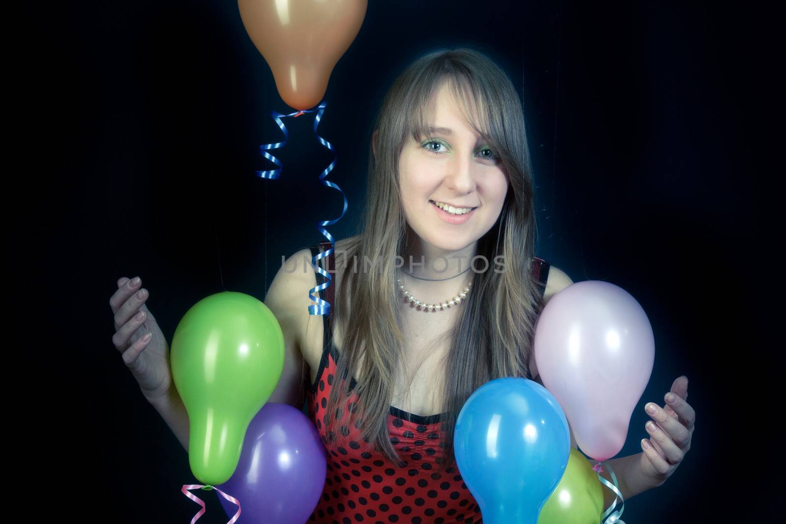 A smiling girl with colorful balloons on a dark background