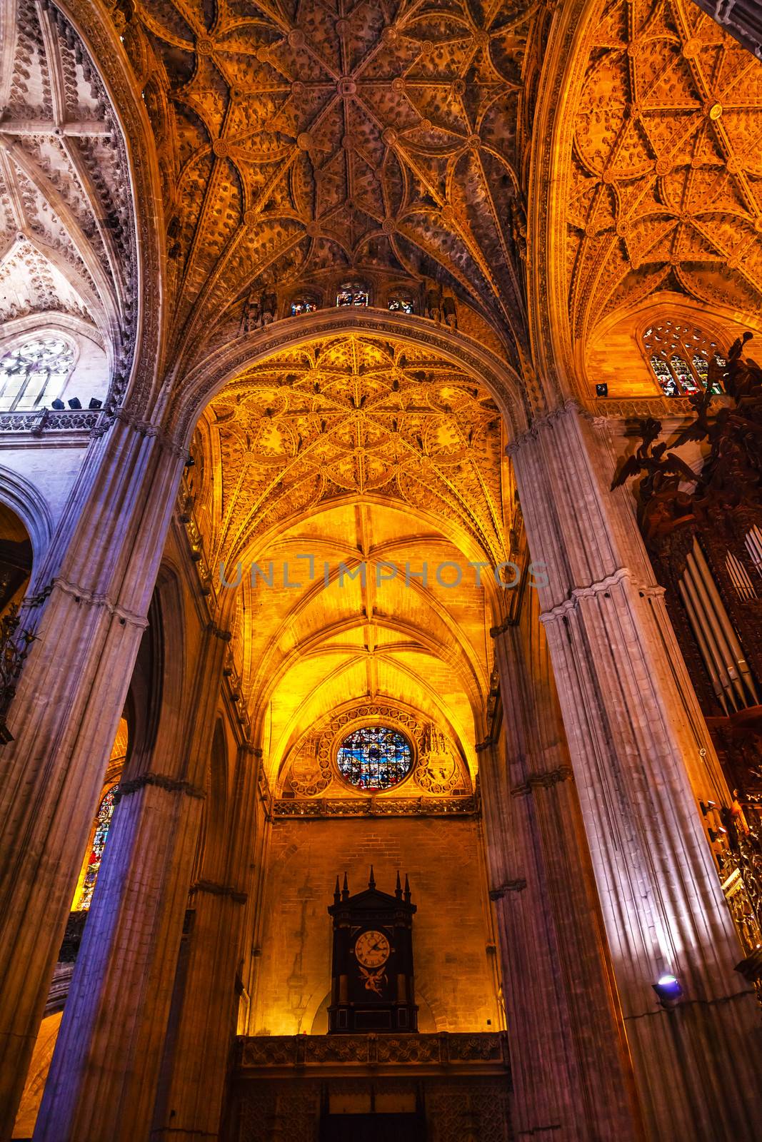 Stone Columns Stained Glass Clock Seville Cathedral, Cathedral of Saint Mary of the See, Seville, Andalusia Spain.  Built in the 1500s.  Largest Gothic Cathedral in the World and Third Largest Church in the World.  Burial Place of Christopher Columbus.