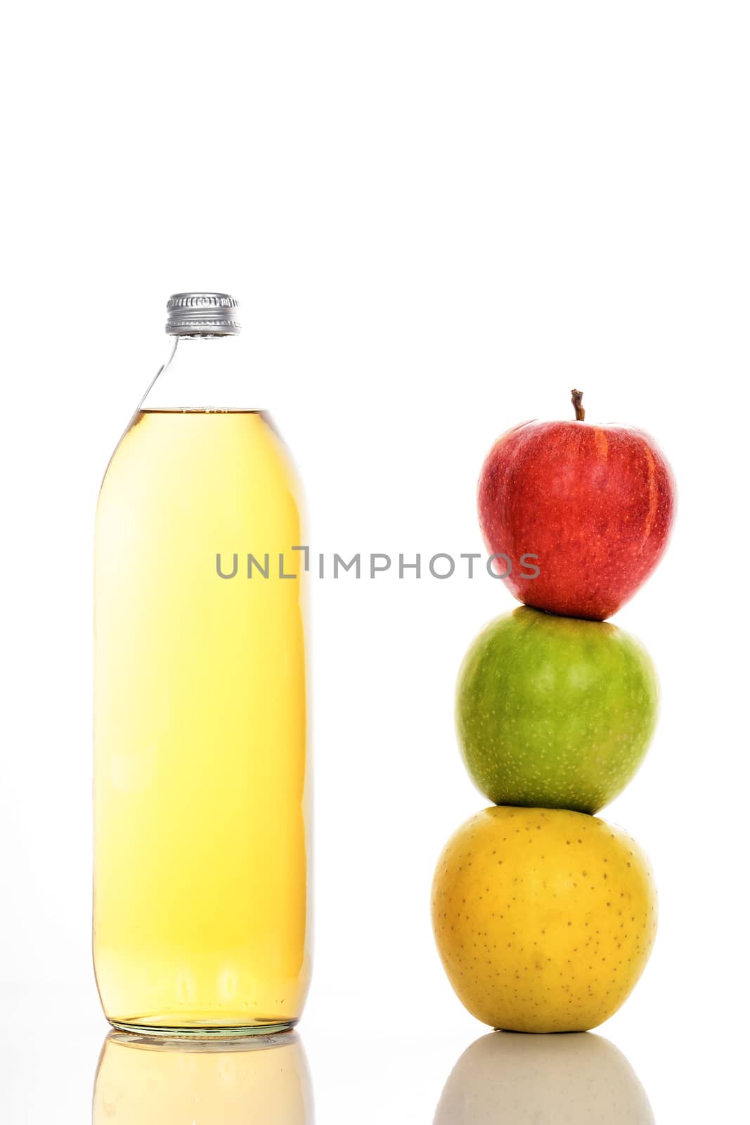 Apple juice in glass bottle and three ripe apples