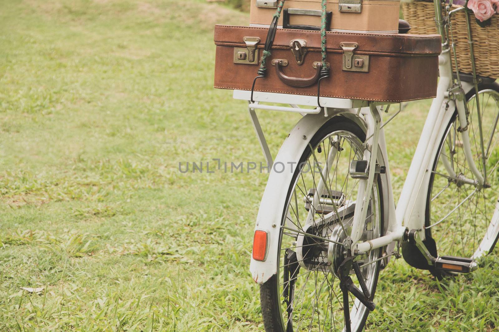 Vintage bicycle on the field with a basket of flowers and bag