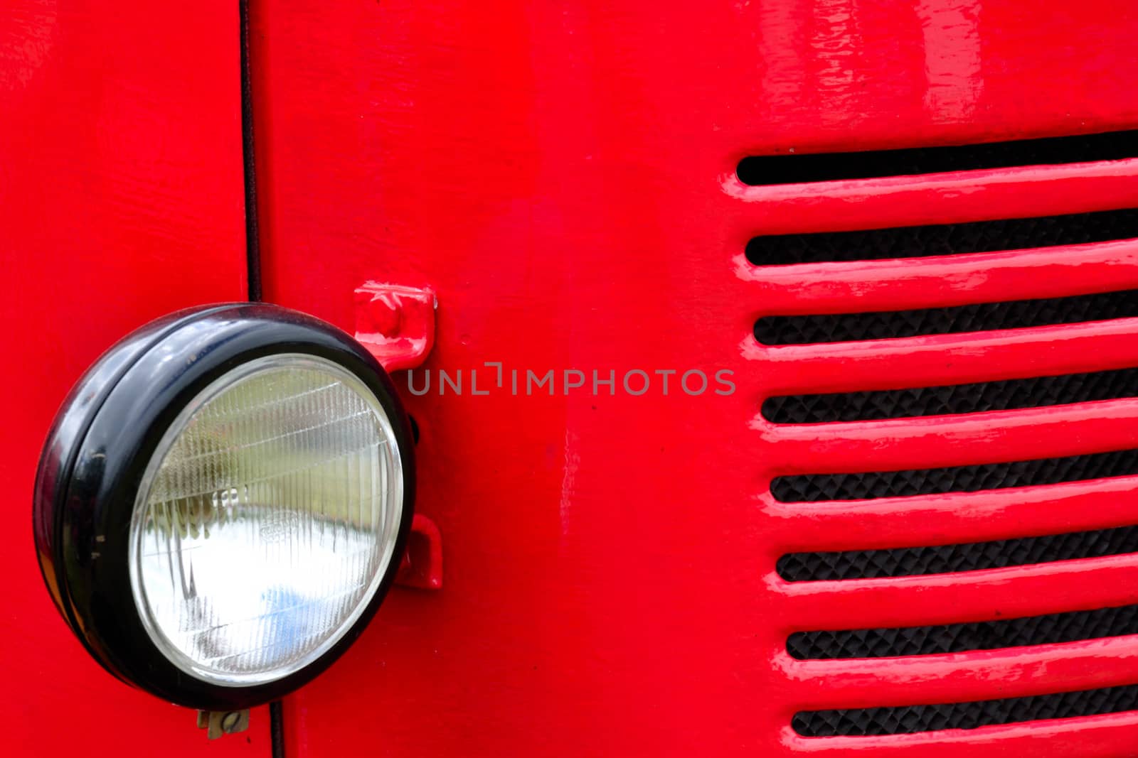 headlight and grill detail of red vehicle