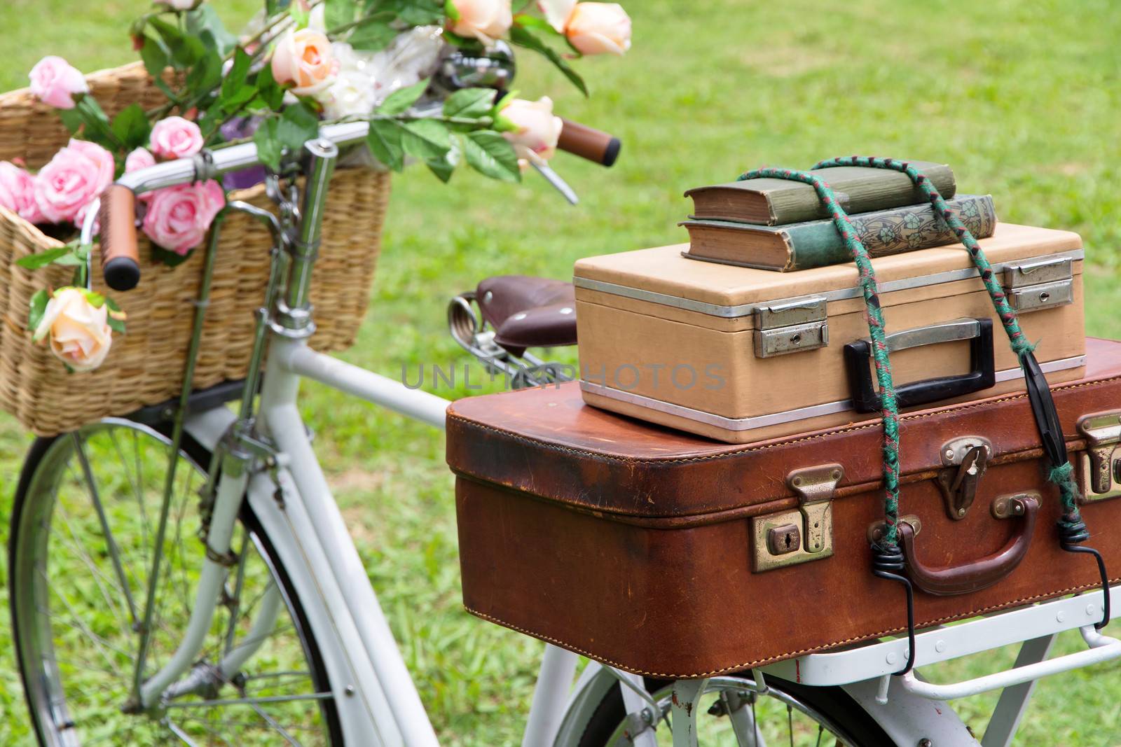 Vintage bicycle on the field with a basket of flowers and bag