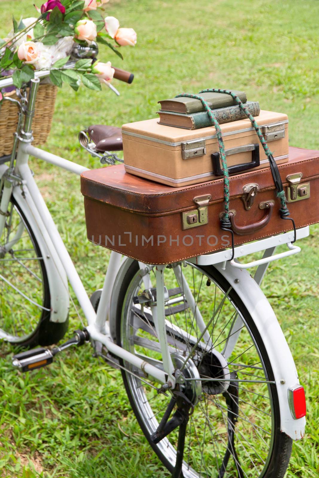 Vintage bicycle on the field with a basket of flowers and bag by ponsulak