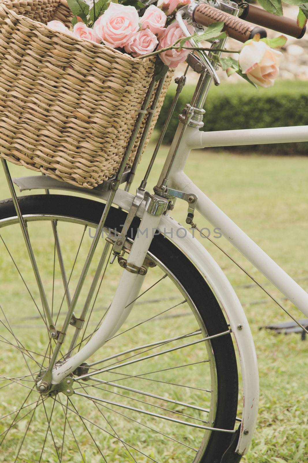 Vintage bicycle on the field with a basket of flowers by ponsulak