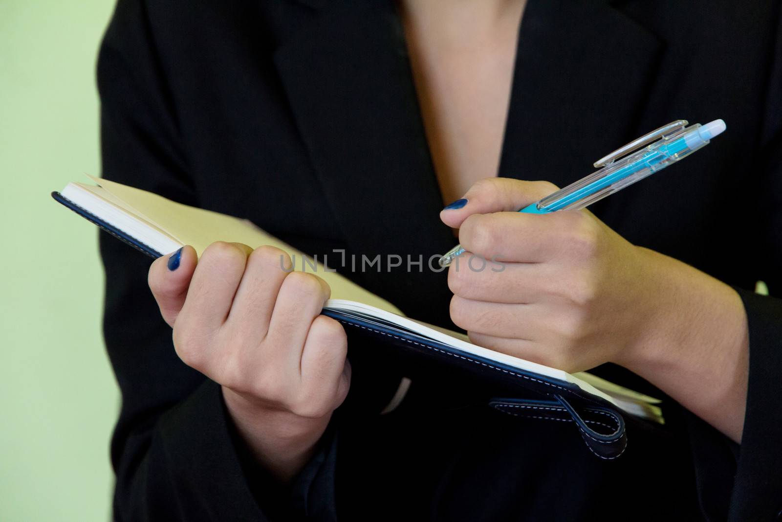Businesswoman writing in notebook. by ponsulak
