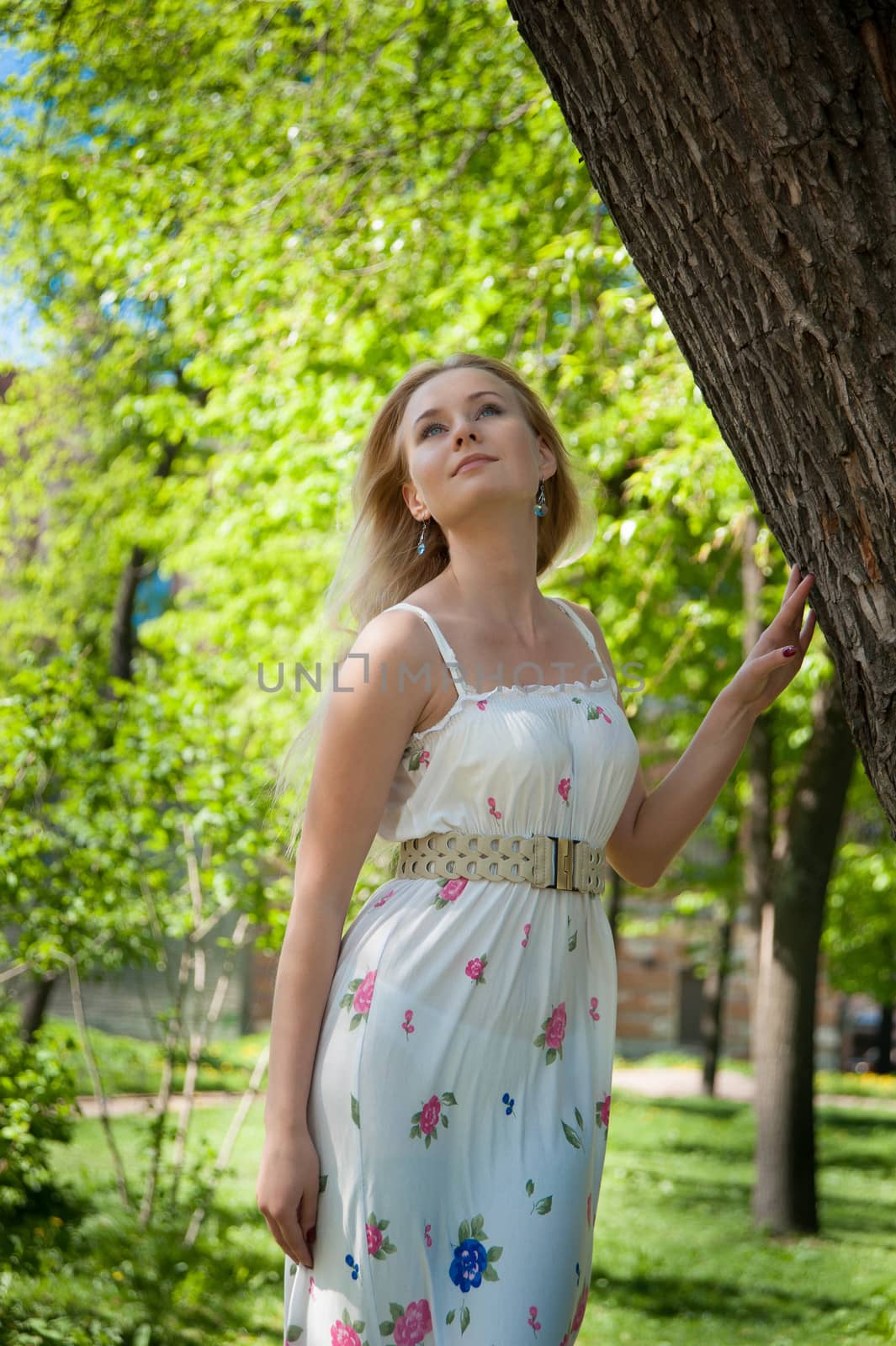 beautiful, young woman standing near the tree in the park