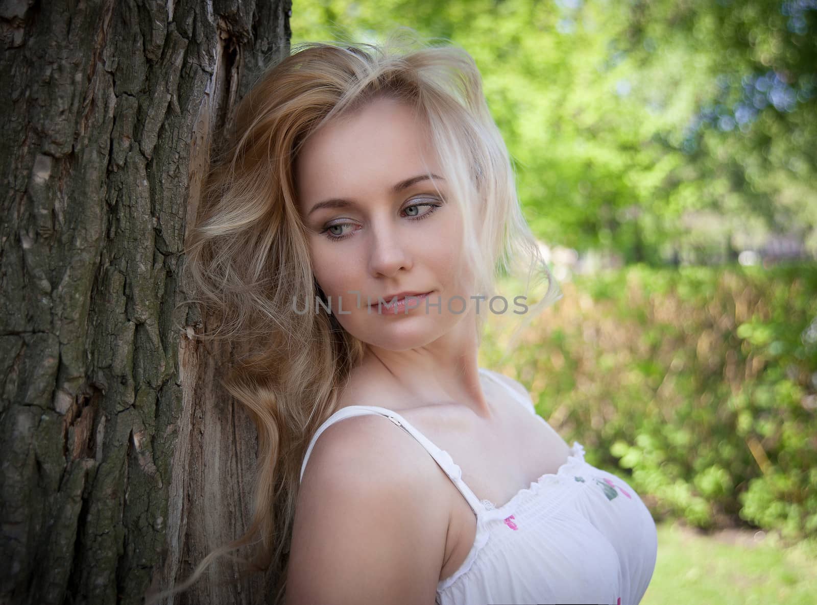 beautiful, young woman standing near the tree in the park