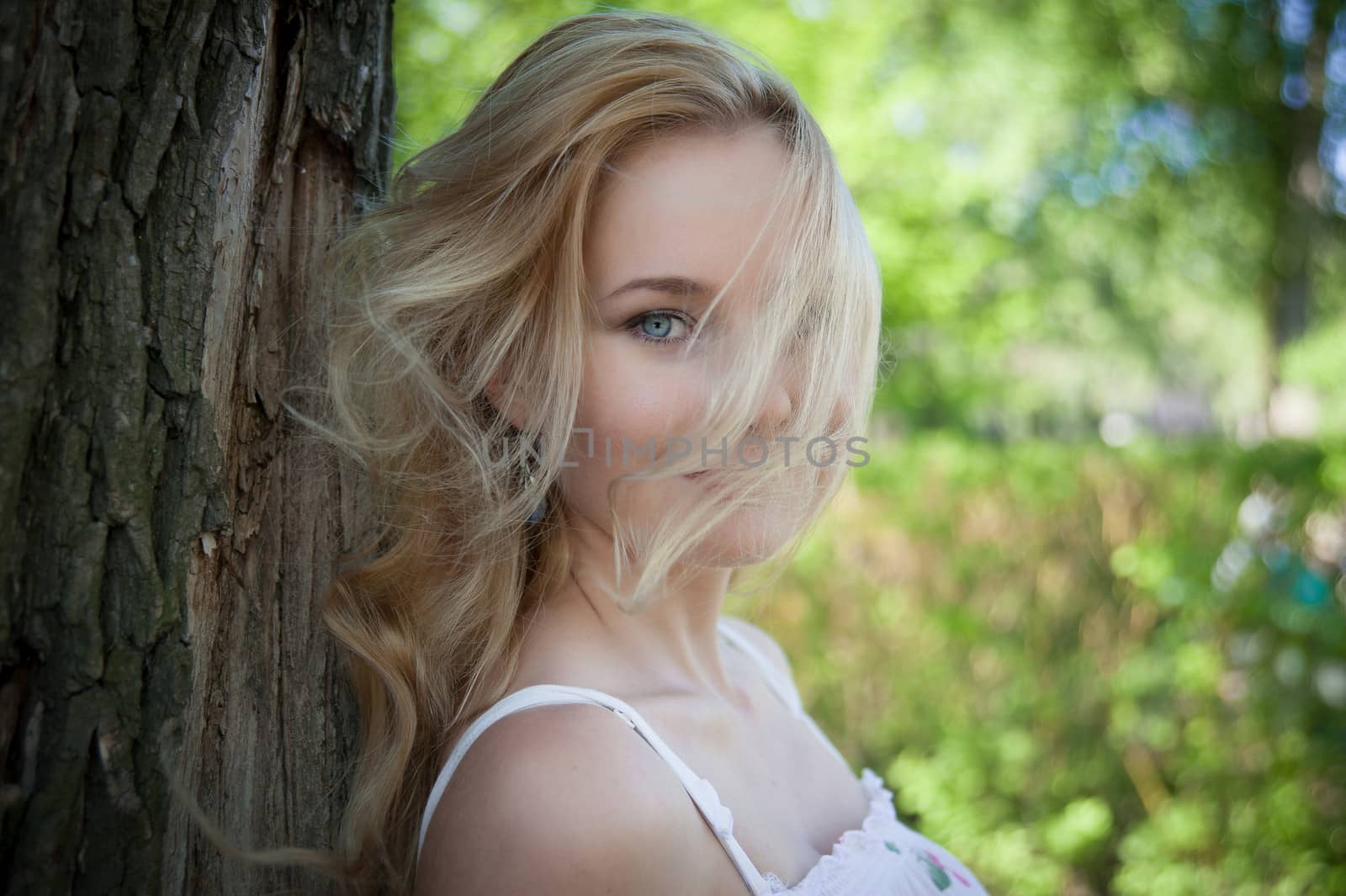 beautiful, young woman standing near the tree in the park