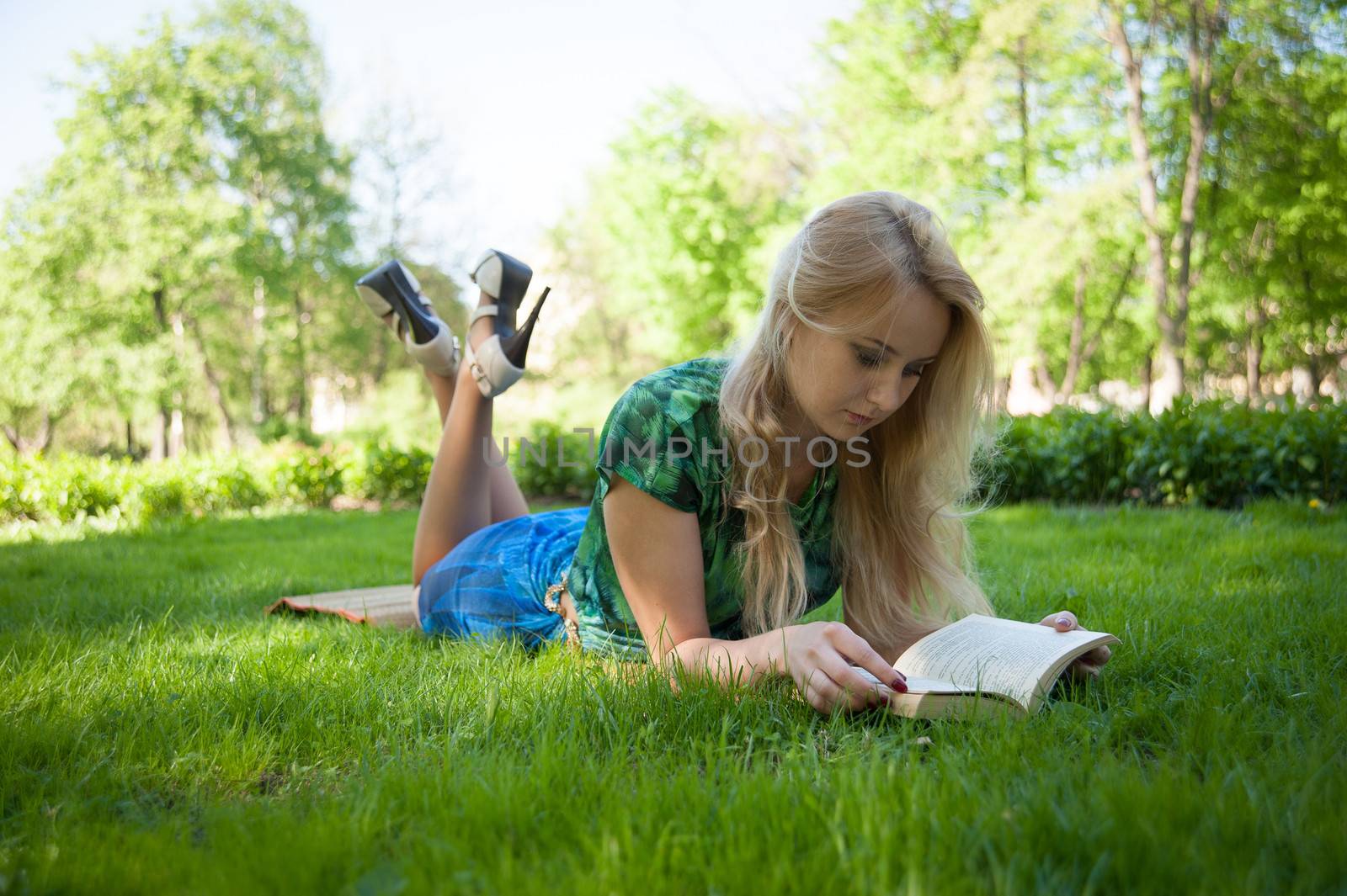 young girl is laying on the grass with a book
