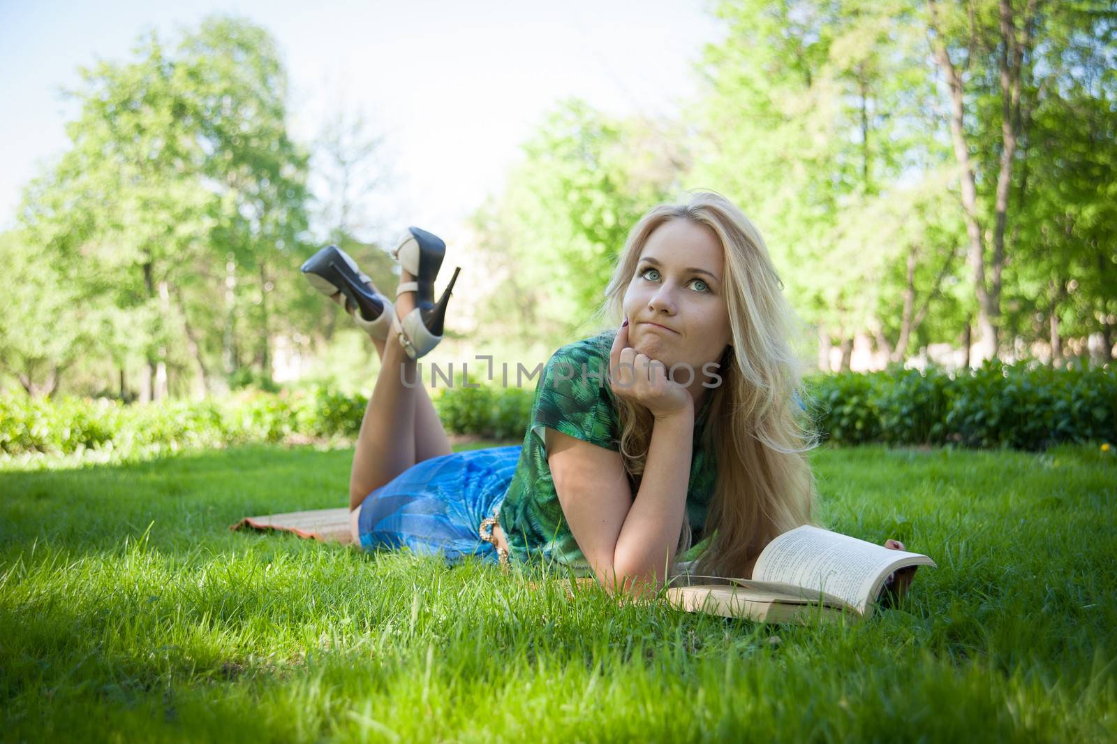 young girl is laying on the grass with a book
