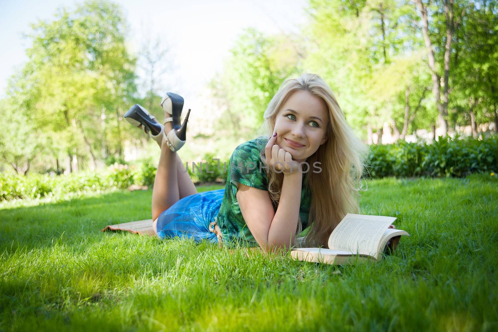 young girl is laying on the grass with a book