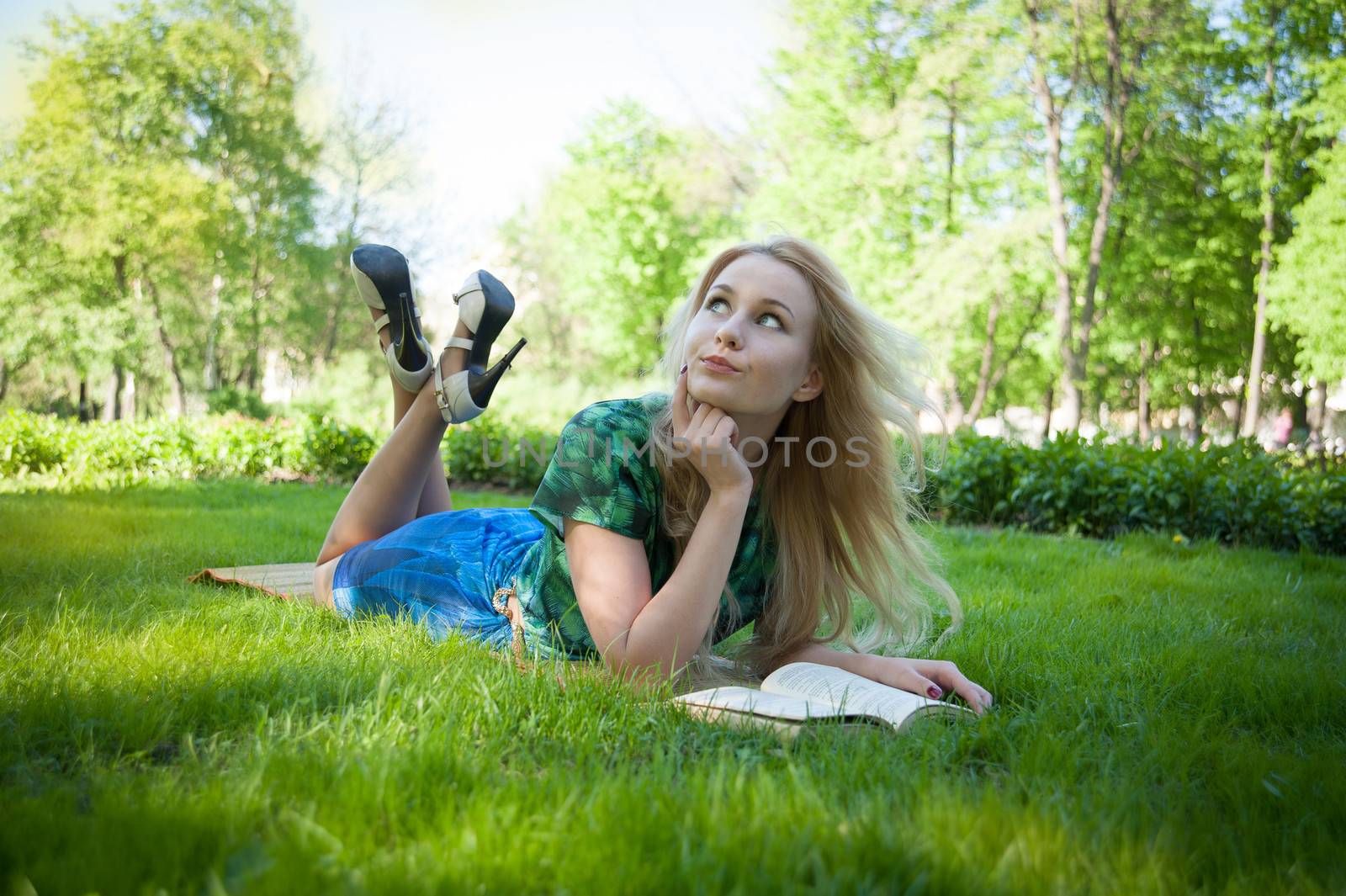 young girl is laying on the grass with a book
