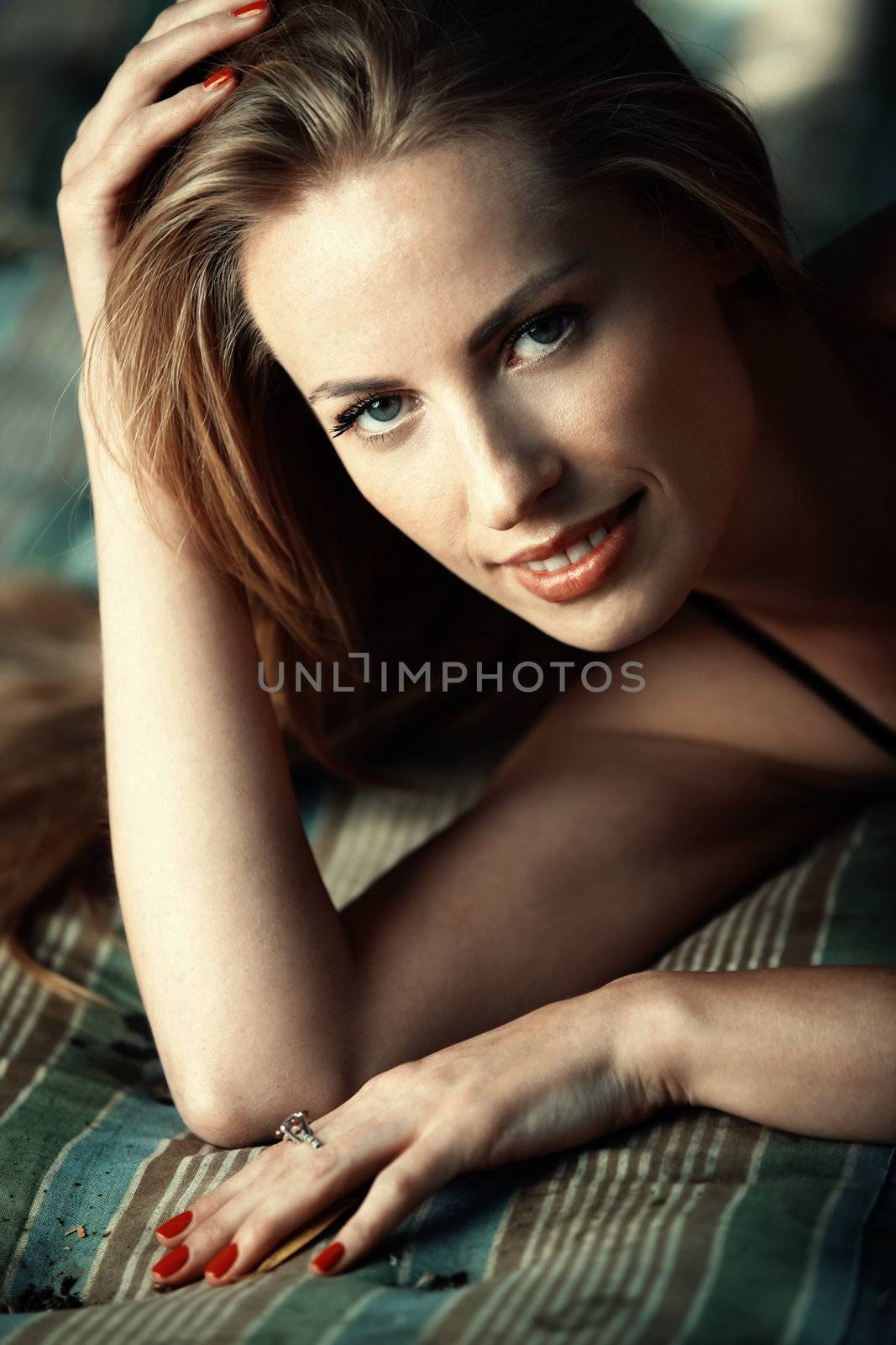 Beautiful smiling lady outdoors laying on a bedding. Close-up