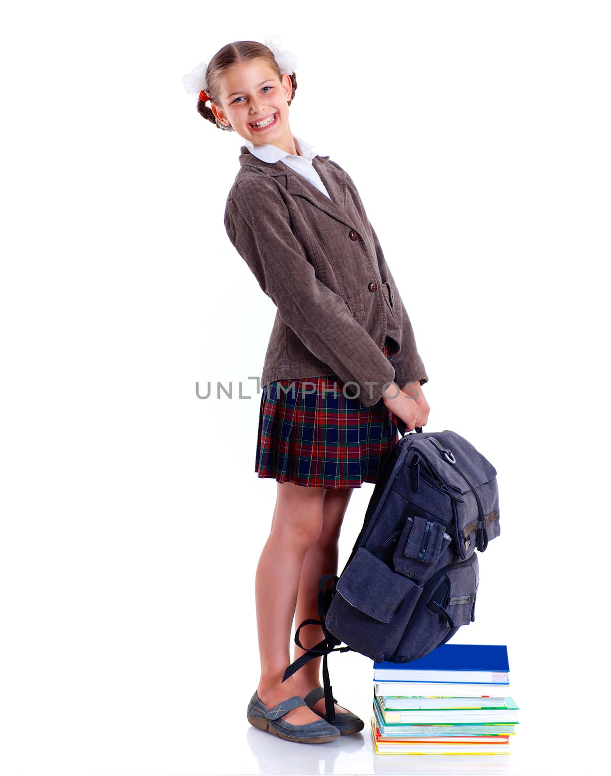 Education theme. Joyful schoolgirl smiling happily with heavy backpack and book. Isolated on white background