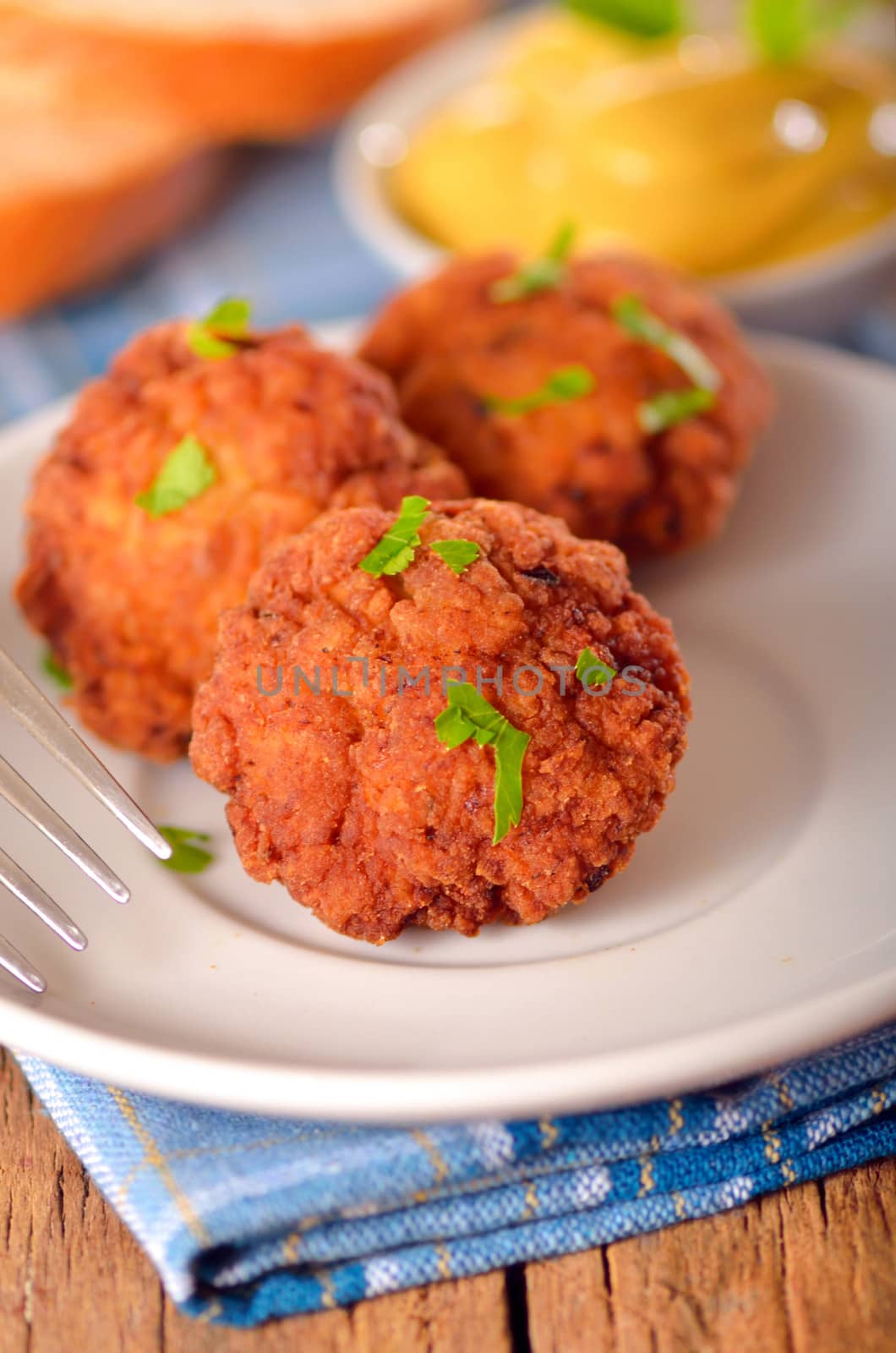  meat balls with mustard on white dish on wooden backgrounds