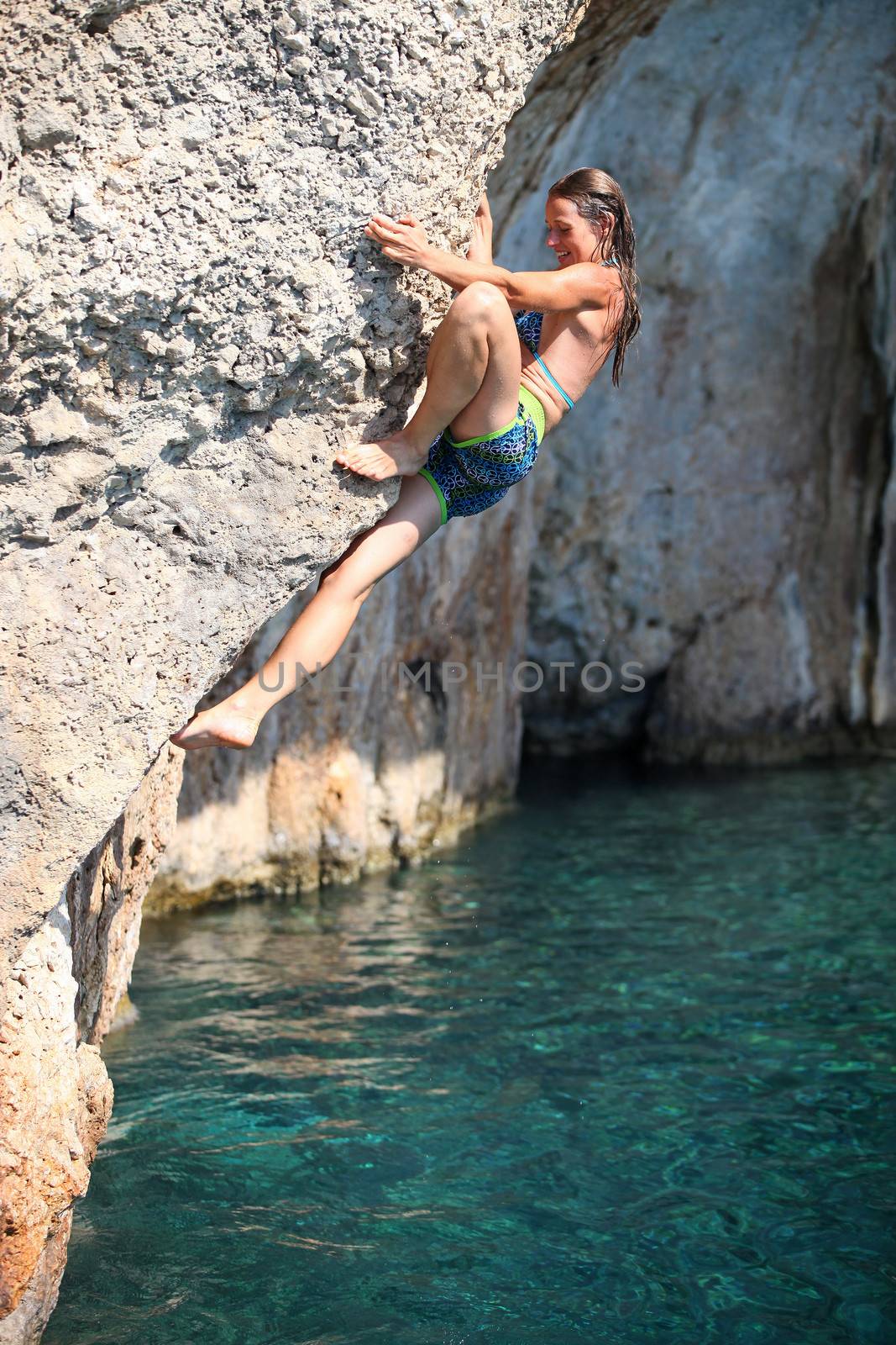 Deep water soloing, female climber on cliff by photobac