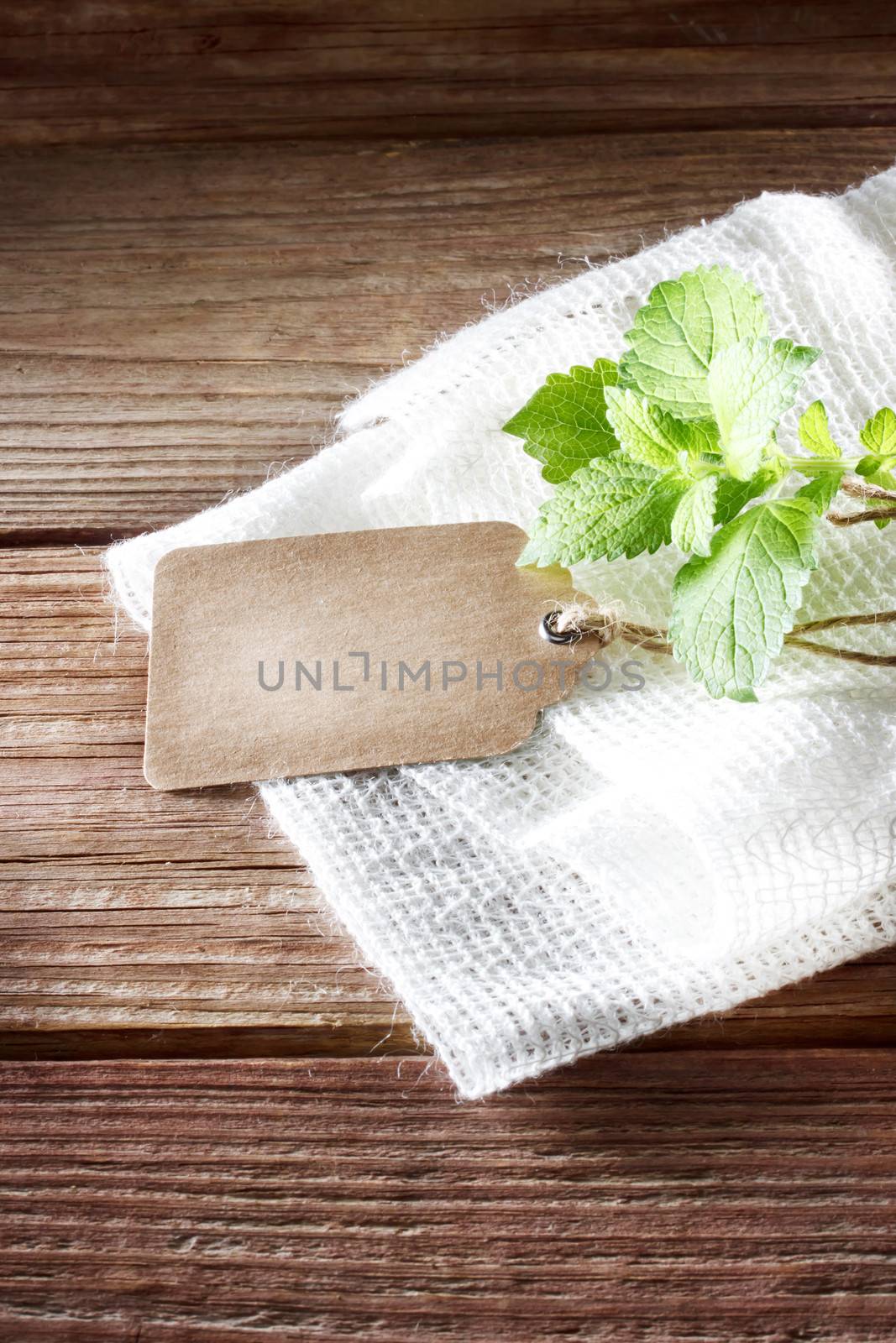 Blank tag on a rustic wooden table with burlap and a sprig of mint 
