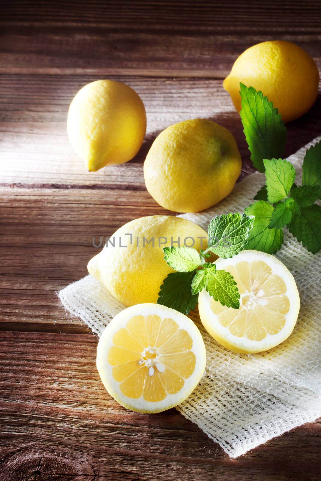 Lemons on a rustic table of wood with a sprig of mint