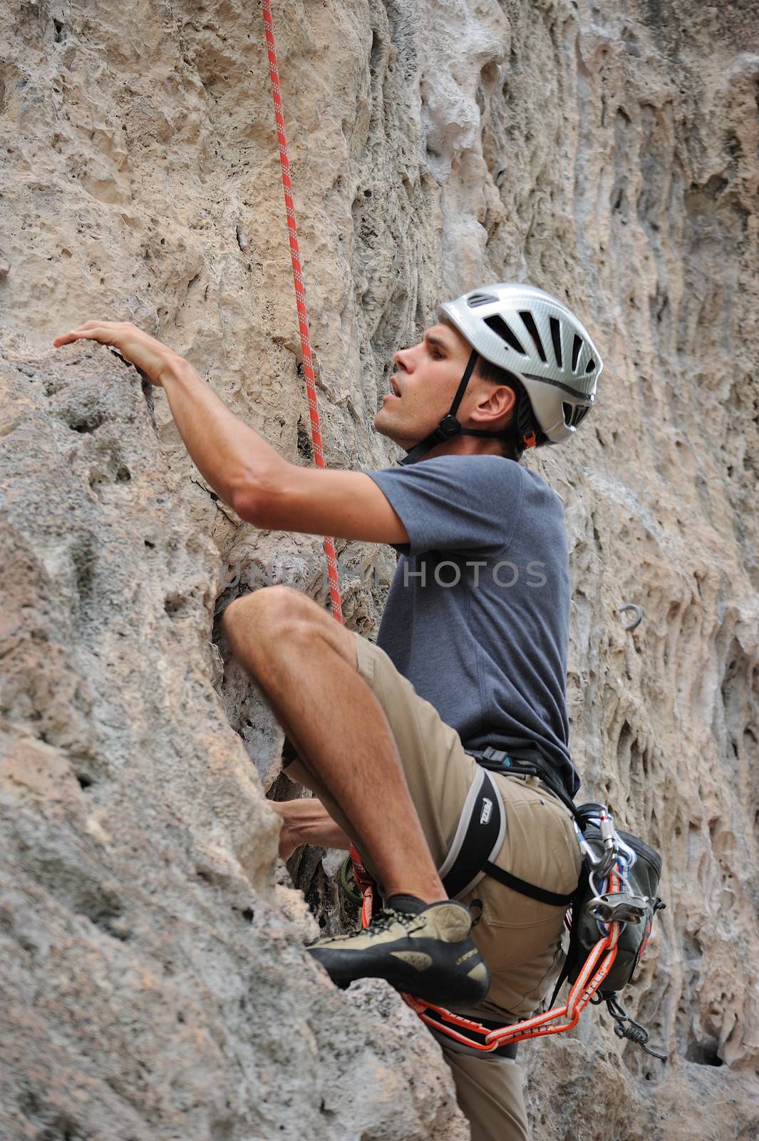 Man climber clinging to a cliff by letoakin