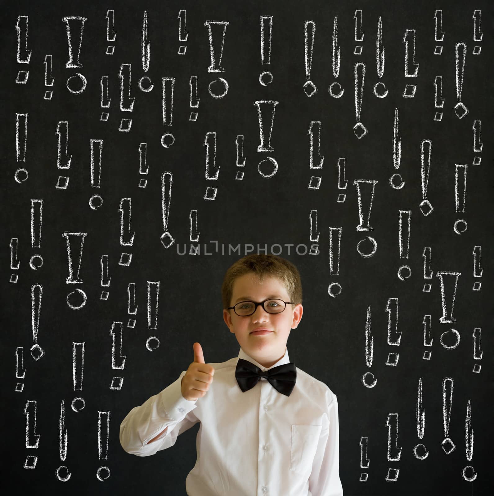 Thumbs up boy dressed up as business man with chalk exclamation marks on blackboard background