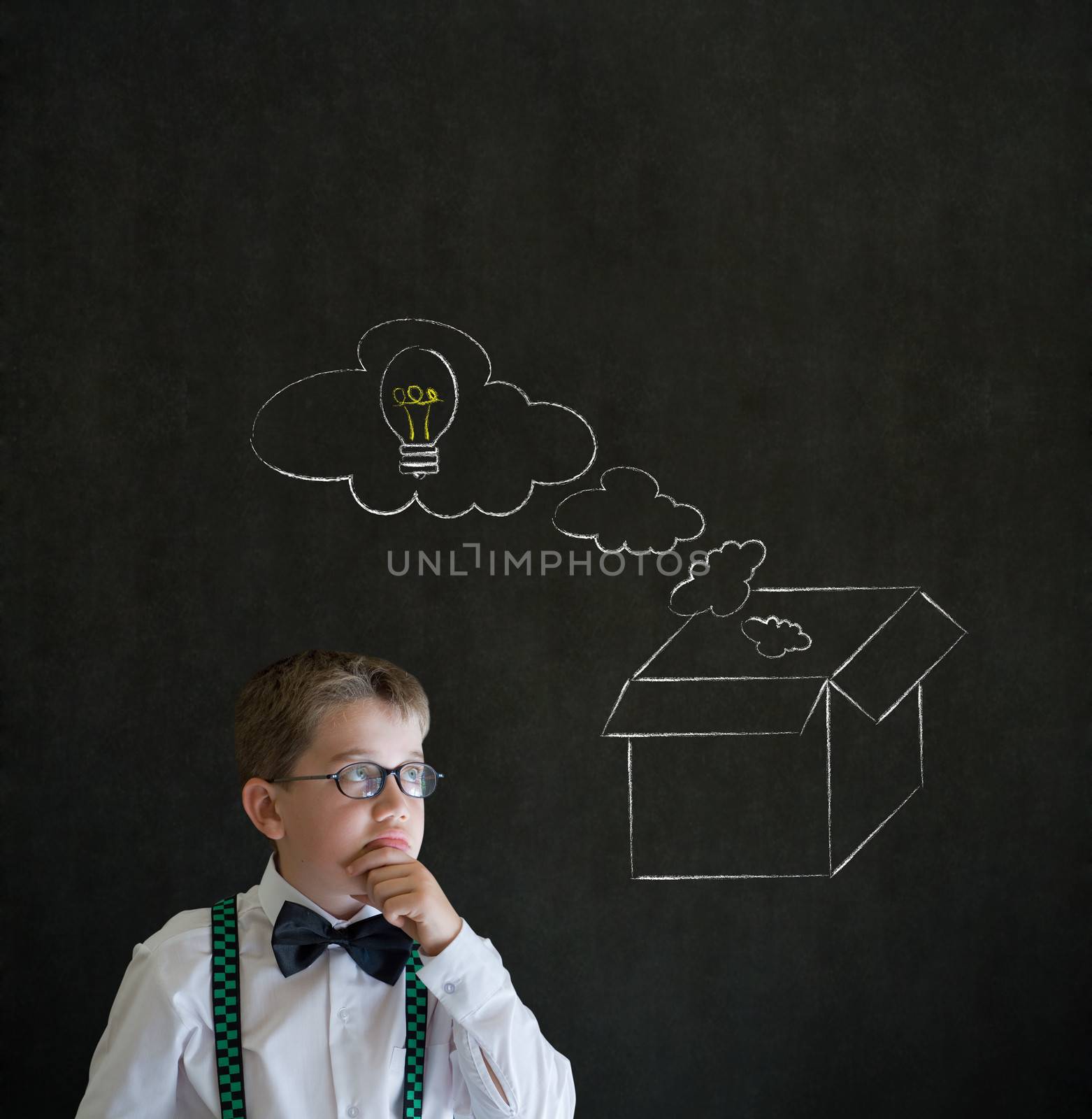 Thinking boy dressed up as business man with chalk thinking out the box concept  on blackboard background