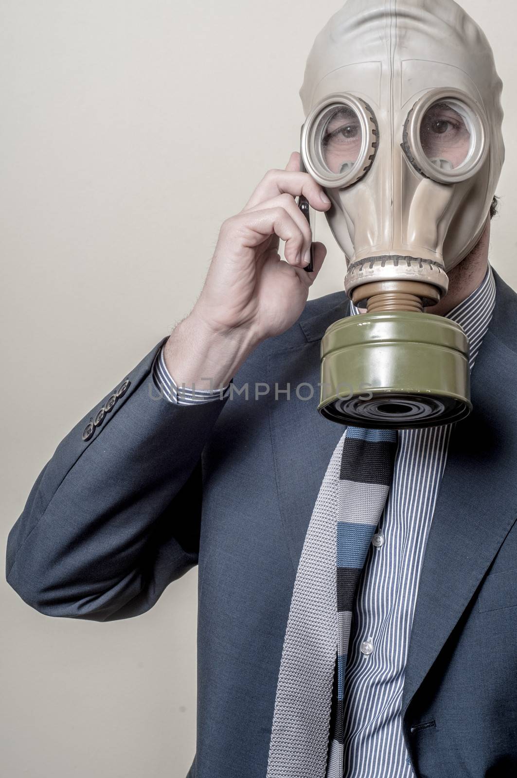 businessman with gas mask with phone on gray background