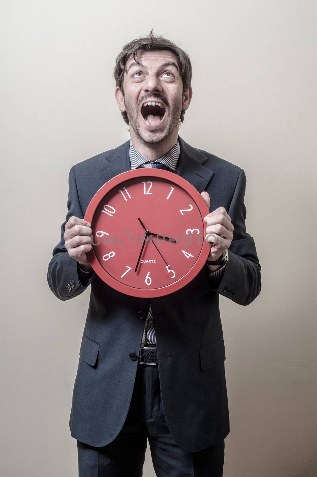businessman with clock screaming on gray background