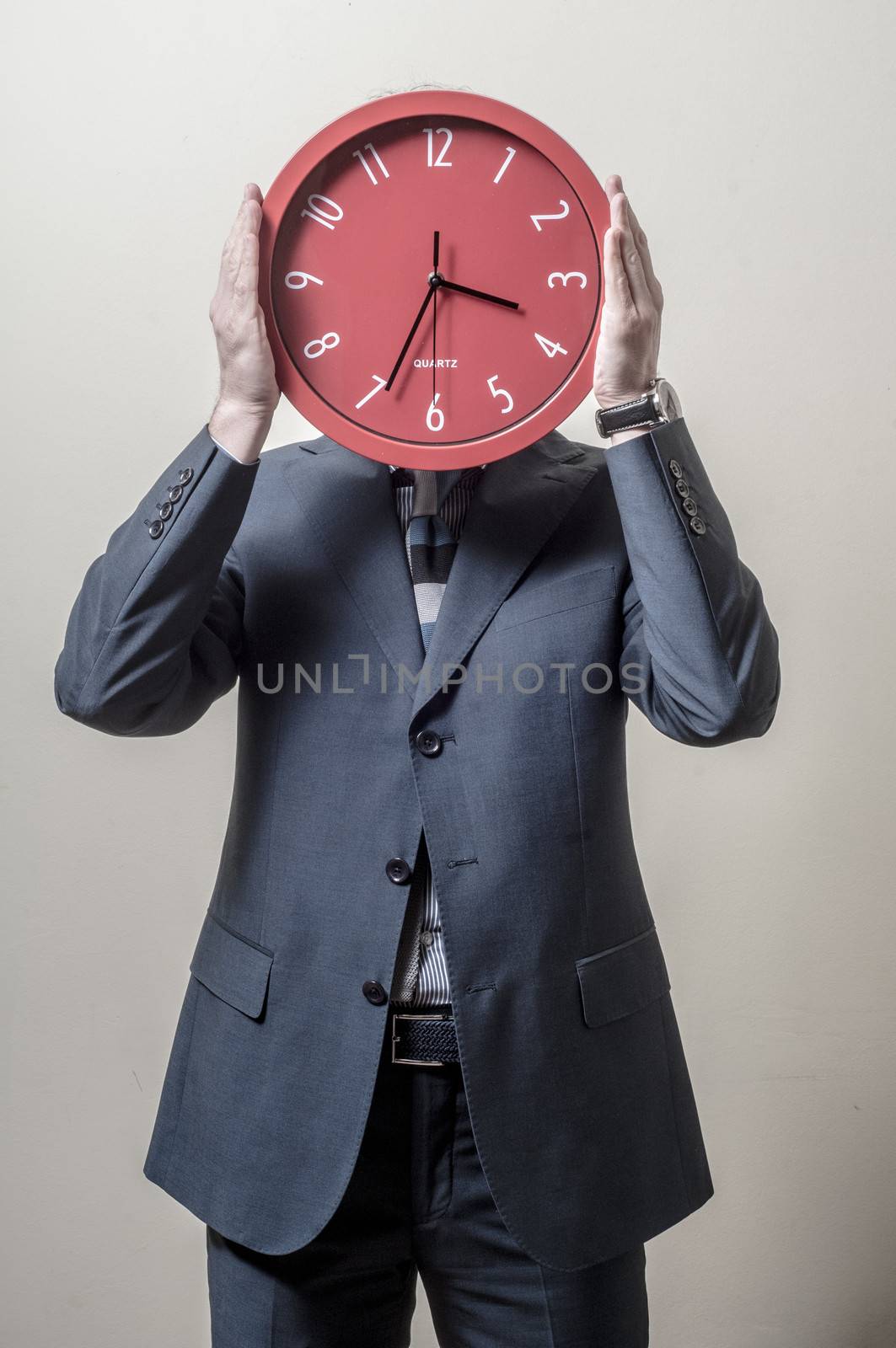 businessman with clock on his head on gray background
