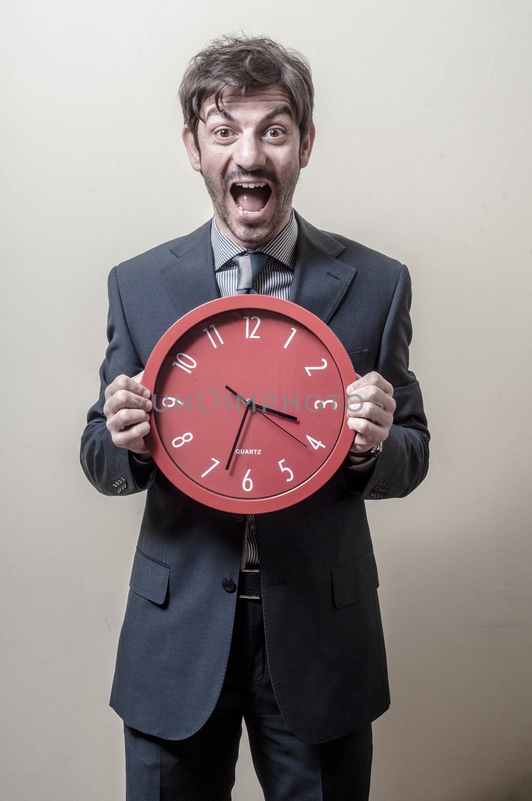 businessman with clock screaming on gray background