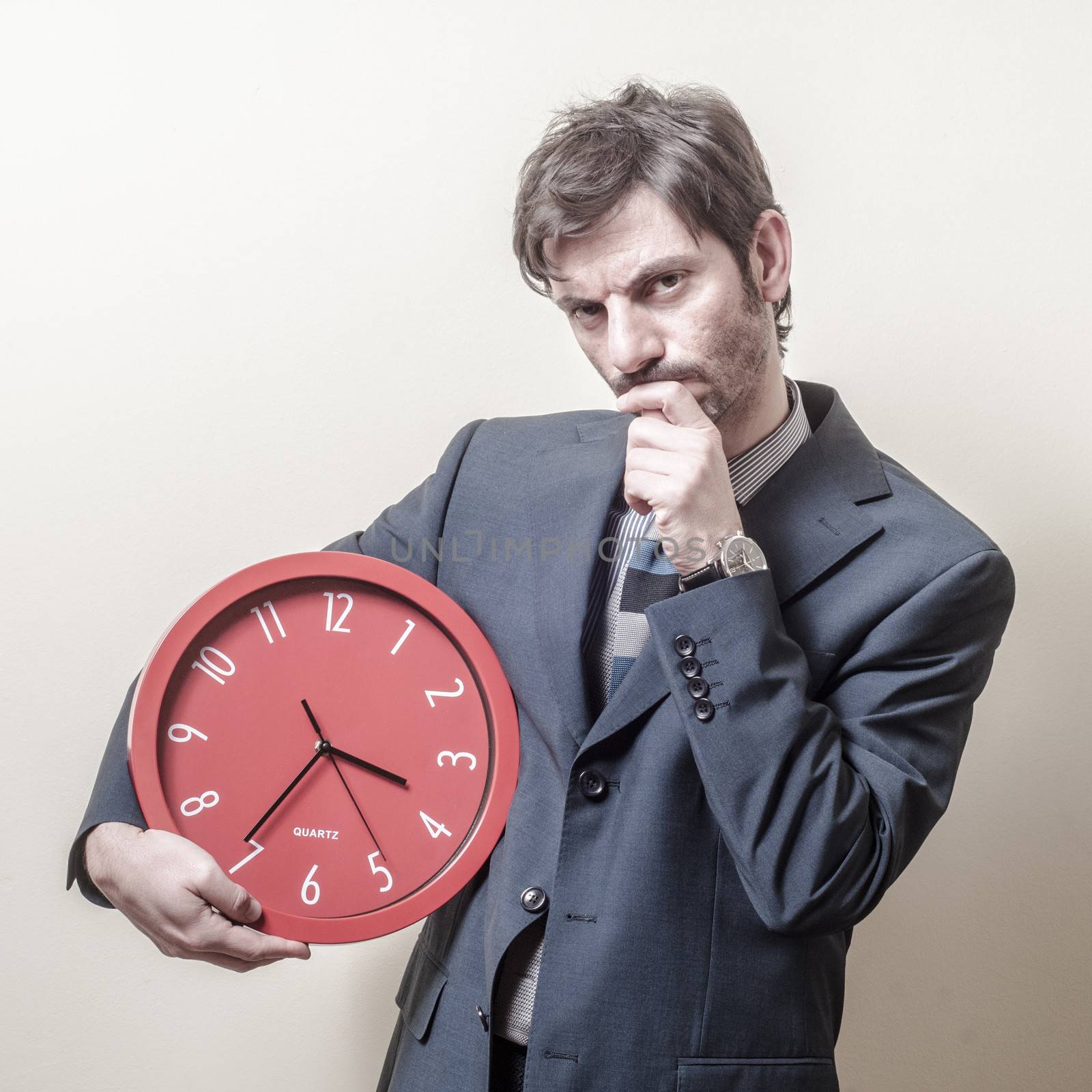 businessman with clock doubtful on gray background